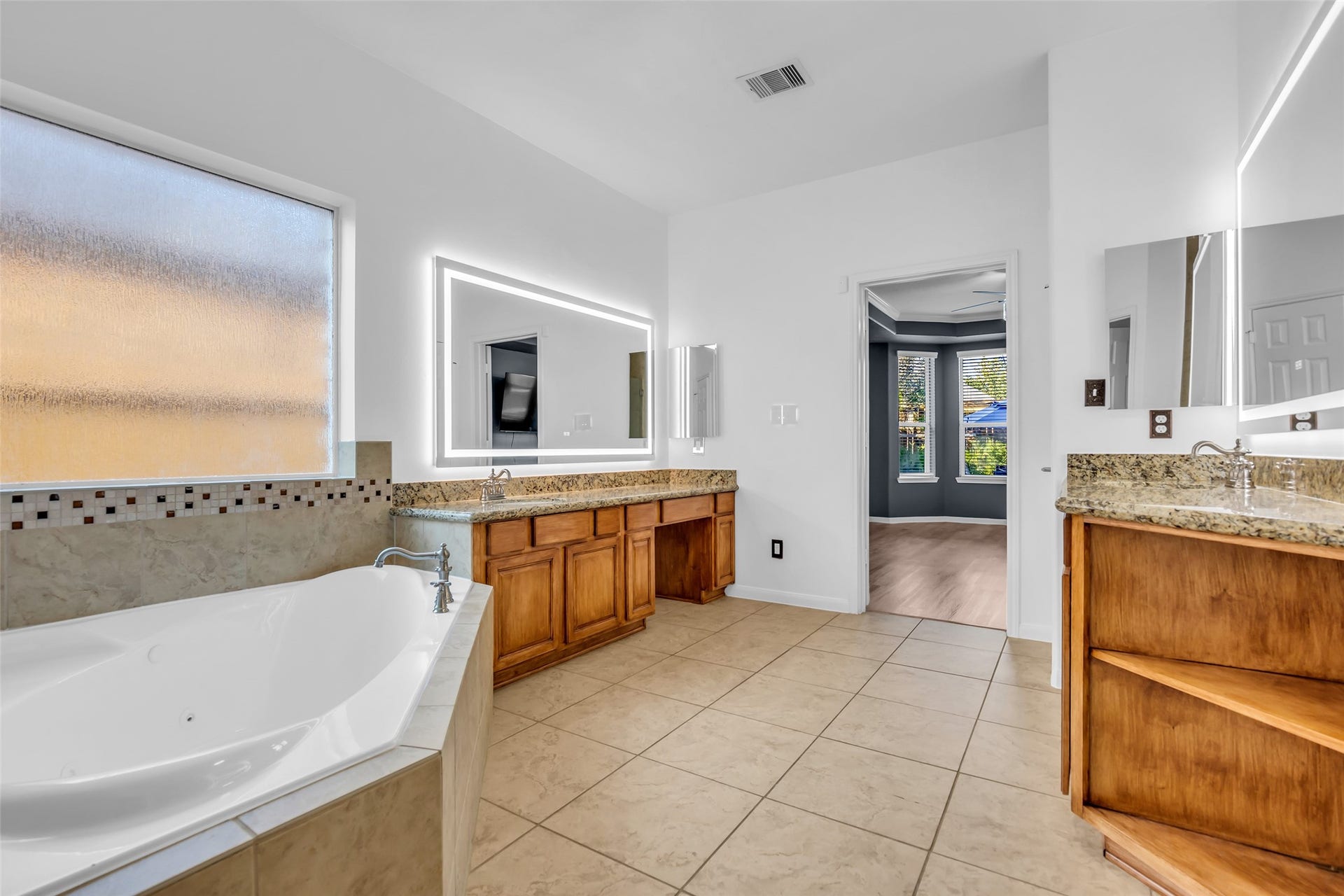 8121 Tranquil Lake Way, Conroe, TX 77385 Spacious primary bathroom featuring a luxurious soaking tub, dual vanities with granite countertops, and elegant tile flooring.