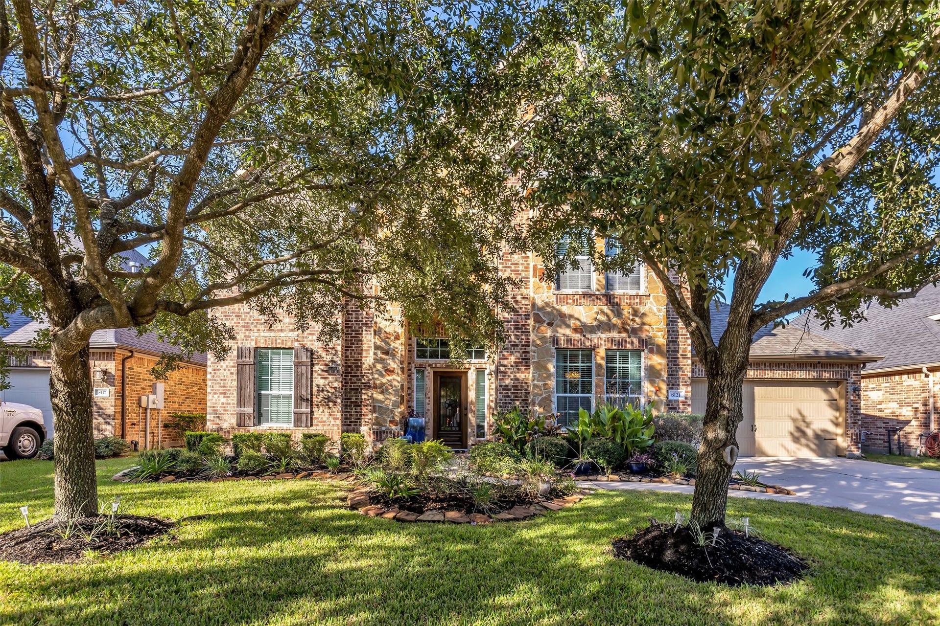 8121 Tranquil Lake Way, Conroe, TX 77385 Charming brick home with lush landscaping, mature trees, and inviting curb appeal in a serene neighborhood.