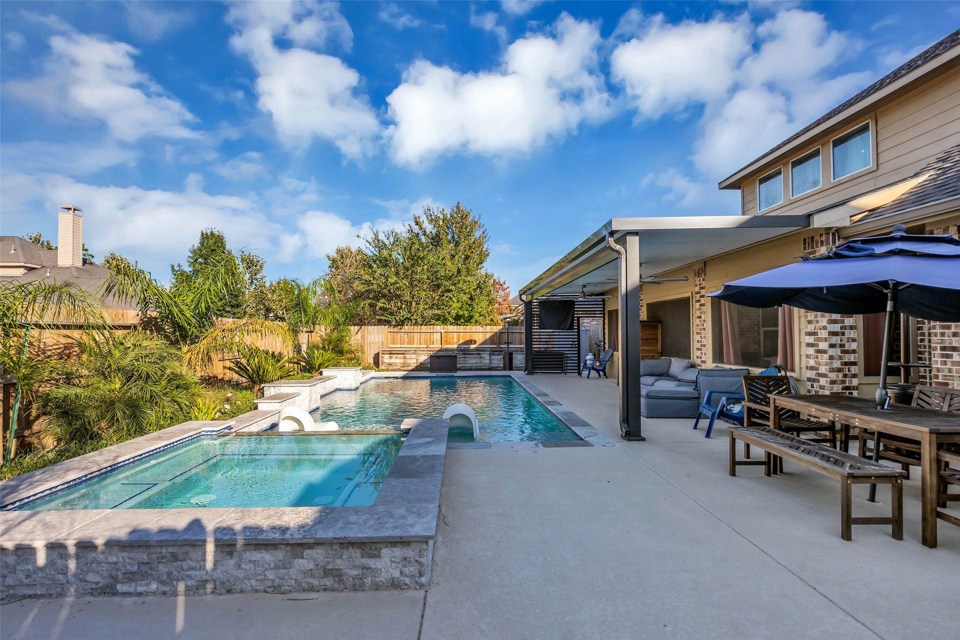 8121 Tranquil Lake Way, Conroe, TX 77385 Stunning backyard oasis featuring a luxurious swimming pool and spa, complemented by a spacious patio with ample seating and dining space under a stylish pergola.