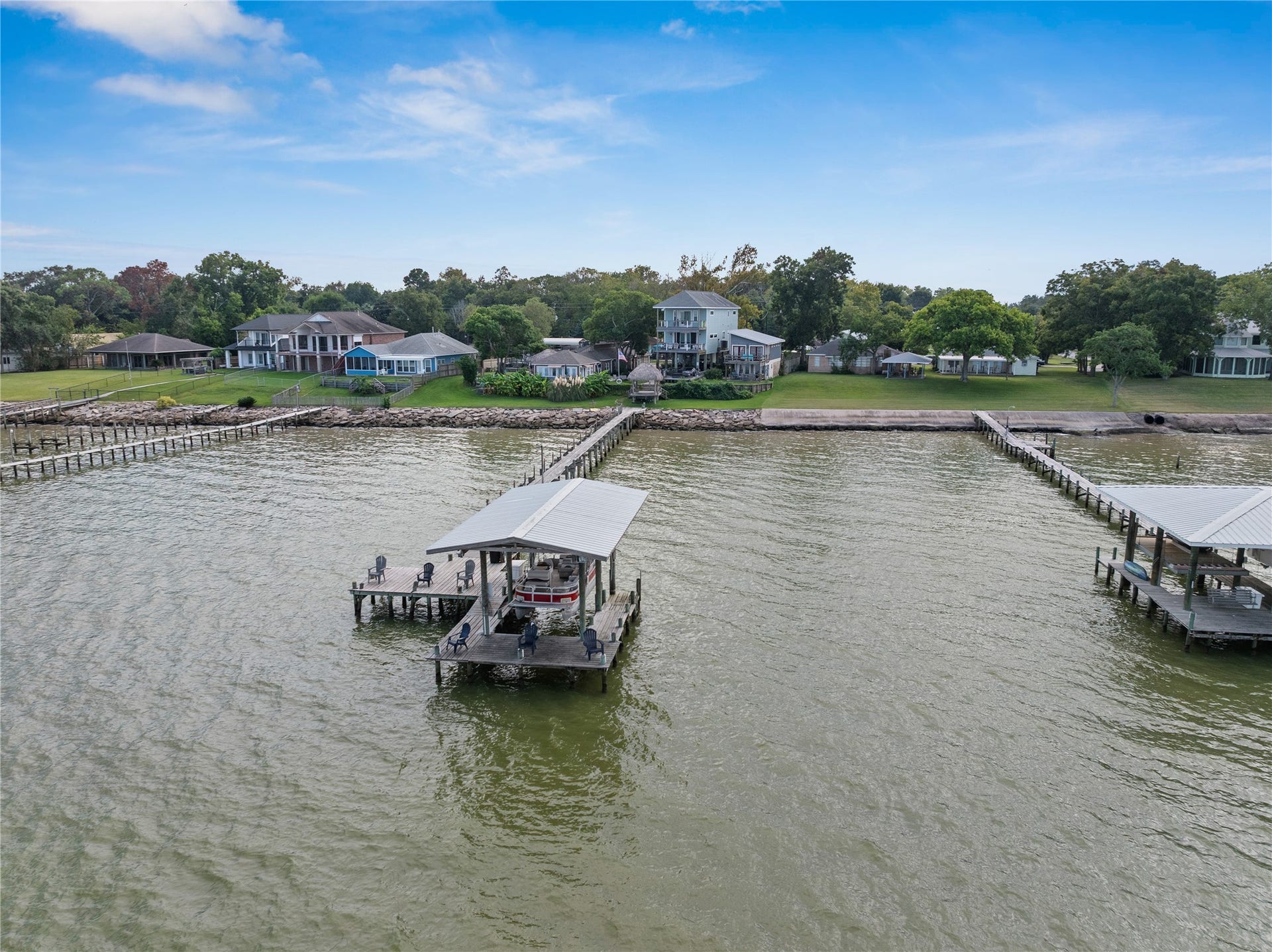 3709 Bayshore Drive, #1-12, Bacliff, TX 77518 This photo showcases the serene waterfront property with a private pier extending into Galveston Bay. The area features well-maintained houses and lush greenery, offering a peaceful and picturesque setting ideal for relaxation and leisure activities.