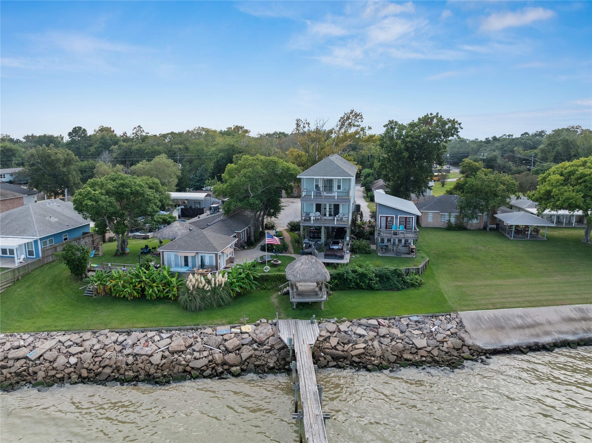 3709 Bayshore Drive, #1-12, Bacliff, TX 77518 Charming waterfront property with a spacious lawn, lush landscaping, and a private pier extending into the water.