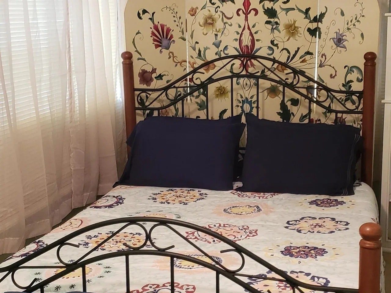 3709 Bayshore Drive, #1-12, Bacliff, TX 77518 Charming bedroom in the Laurel Anne featuring a decorative wrought iron bed frame, vibrant floral accents, and abundant natural light. Perfect for a cozy retreat.