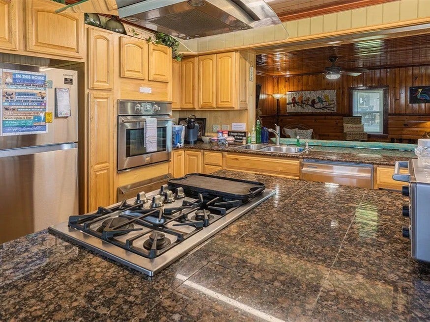 3709 Bayshore Drive, #1-12, Bacliff, TX 77518 Inviting kitchen in the Ohana House with sleek granite countertops, a modern gas stove, and warm wooden cabinetry, perfect for culinary enthusiasts.