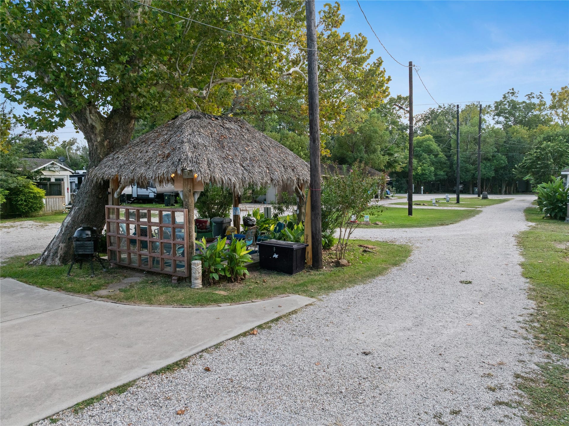 3709 Bayshore Drive, #1-12, Bacliff, TX 77518 This photo showcases a serene outdoor setting featuring a gravel path, lush greenery, and a charming palapa. It's an inviting space ideal for relaxation and enjoying nature.