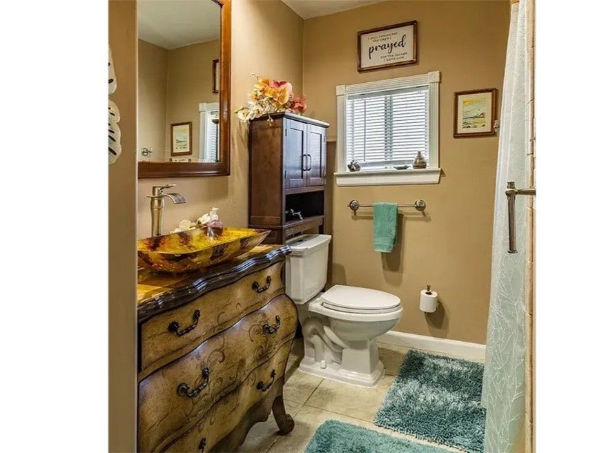 3709 Bayshore Drive, #1-12, Bacliff, TX 77518 Experience elegance in the Ohana House bathroom, featuring a stylish vessel sink, rich wooden cabinetry, and serene neutral tones.