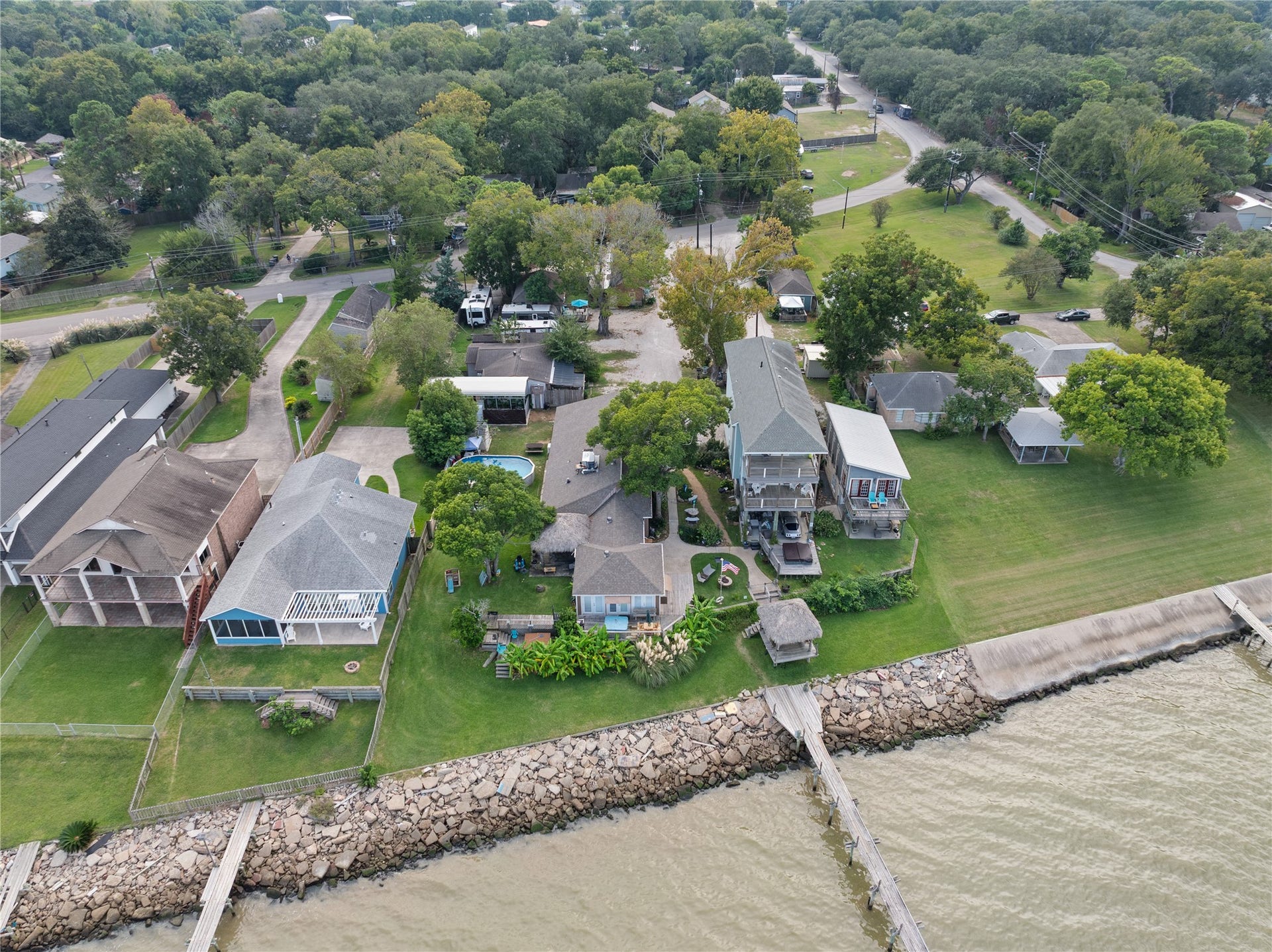 3709 Bayshore Drive, #1-12, Bacliff, TX 77518 This aerial photo showcases a row of charming waterfront homes adjacent to the subject property with spacious yards and direct access to the shoreline. The neighborhood appears tranquil, with well-maintained properties and a mix of architectural styles.