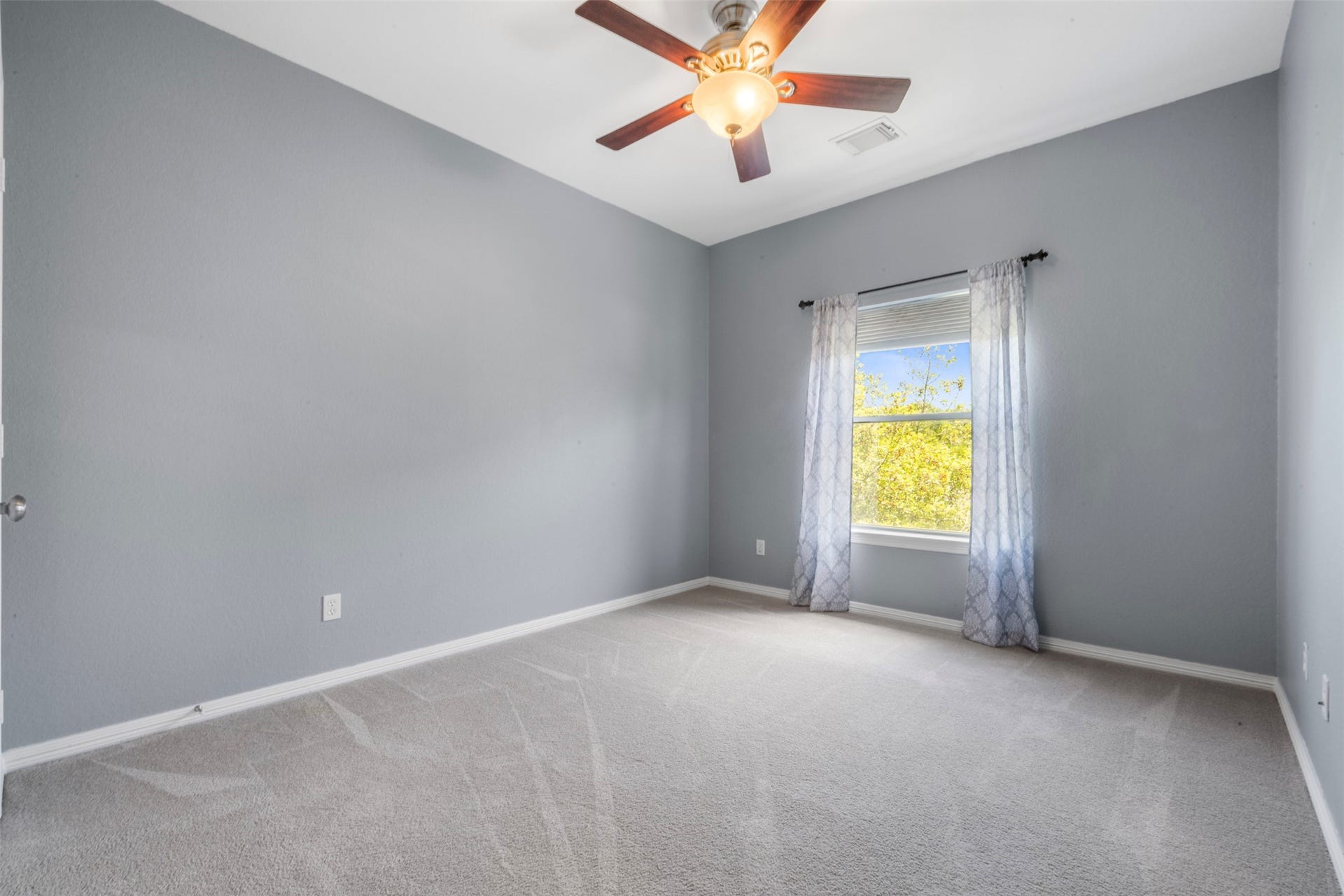 26418 Cottage Cypress Lane, Cypress, TX 77433 A secondary bedroom featuring a large window that gives abundant natural light, and a soaring tray ceiling with a ceiling fan for added comfort. it is part of a jack-and-jill bedroom on the 2nd floor.