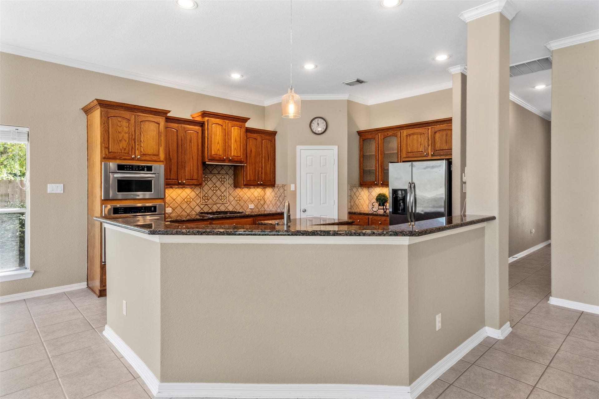 26418 Cottage Cypress Lane, Cypress, TX 77433 This beautifully designed kitchen offers both functionality and style, featuring expansive granite countertops and an abundance of cabinetry with added hardware for a polished look. The open layout provides ample workspace and storage, making it ideal for everyday living and entertaining. Stainless steel appliances complement the warm cabinetry, while the large breakfast bar offers additional seating and a natural gathering space.