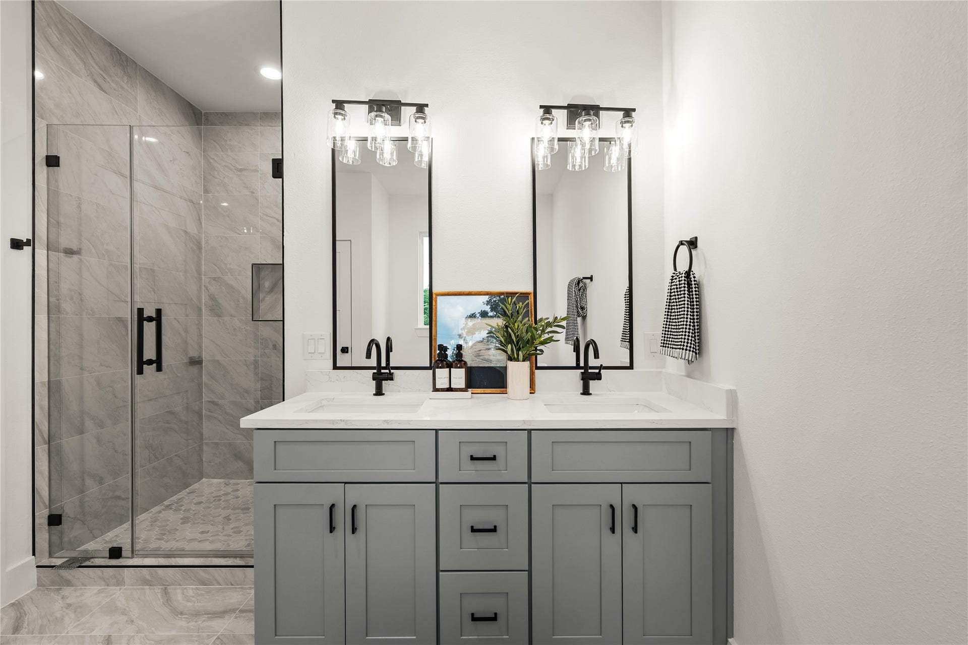 3412 Cortlandt Street, Houston, TX 77018 A double vanity anchors the primary bath, where tall mirrors and clear-glass light fixtures pair with quartz
countertops and soft gray Shaker cabinetry for a refined, symmetrical look.