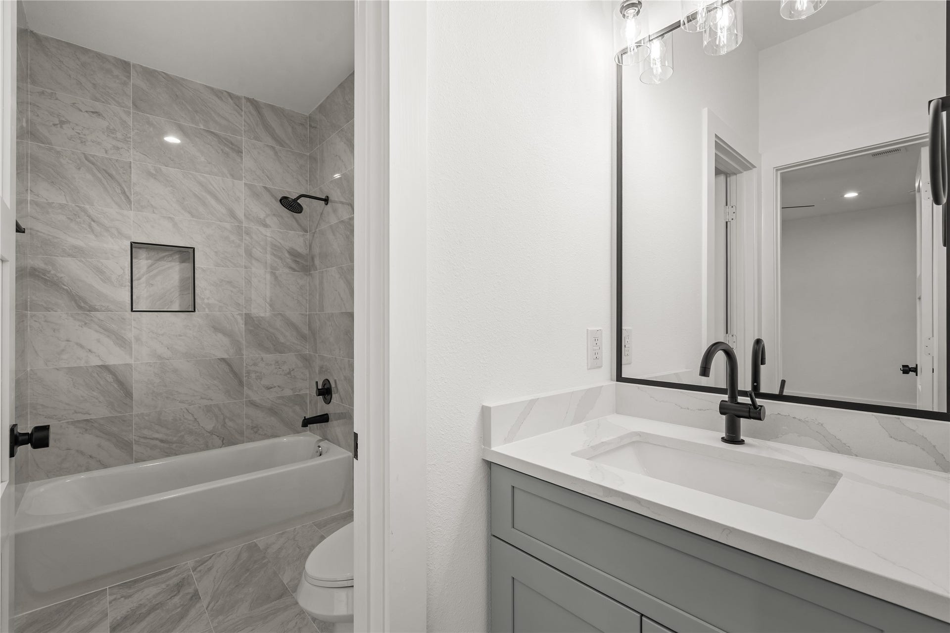 3412 Cortlandt Street, Houston, TX 77018 The secondary bath is finished with floor-to-ceiling marble-look tile around the tub-shower combination, a
built-in niche, and a quartz-topped vanity with the matte-black fixtures carried throughout the home.