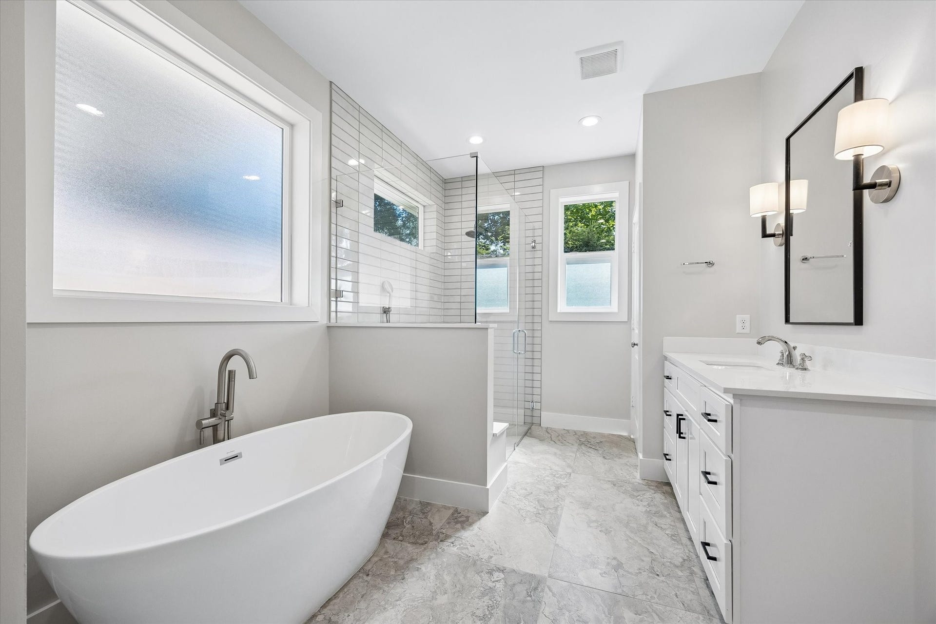 10659 Mayfield Road, Houston, TX 77043 The primary bathroom offers a luxurious retreat with a sleek freestanding tub and a spacious walk-in shower with fashionable tile work.