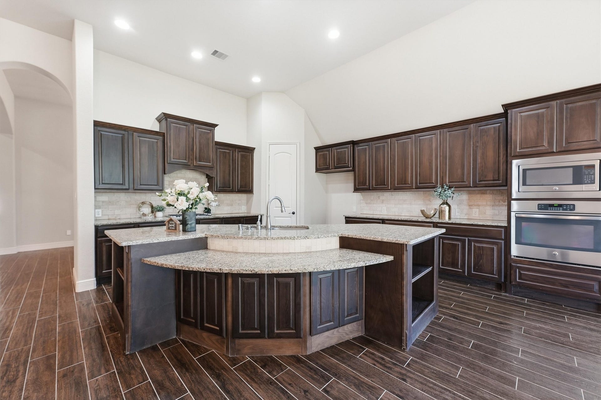 Open kitchen featuring granite countertops, 42-inch cabinetry, and a large center island with seatings.