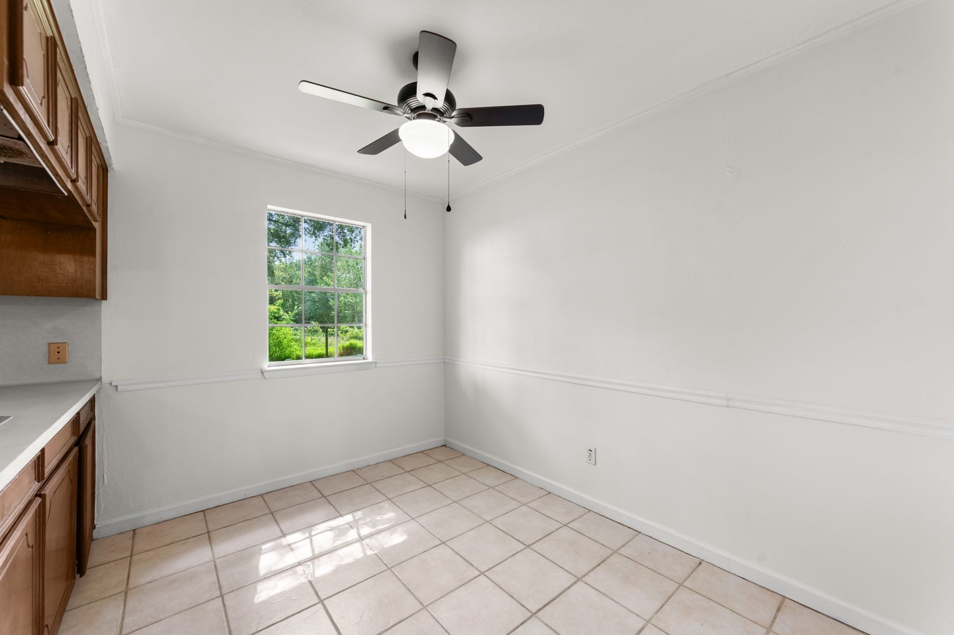 11325 32nd Street, Santa Fe, TX 77510 Bright dining area featuring tile flooring, chair rail molding, a ceiling fan, and a window overlooking the greenery outside. A welcoming space for everyday meals and gatherings.