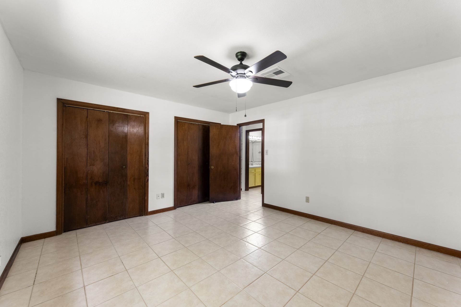 11325 32nd Street, Santa Fe, TX 77510 Another view of the primary suite highlights two closets, a ceiling fan, and convenient access to the adjoining bathroom.
