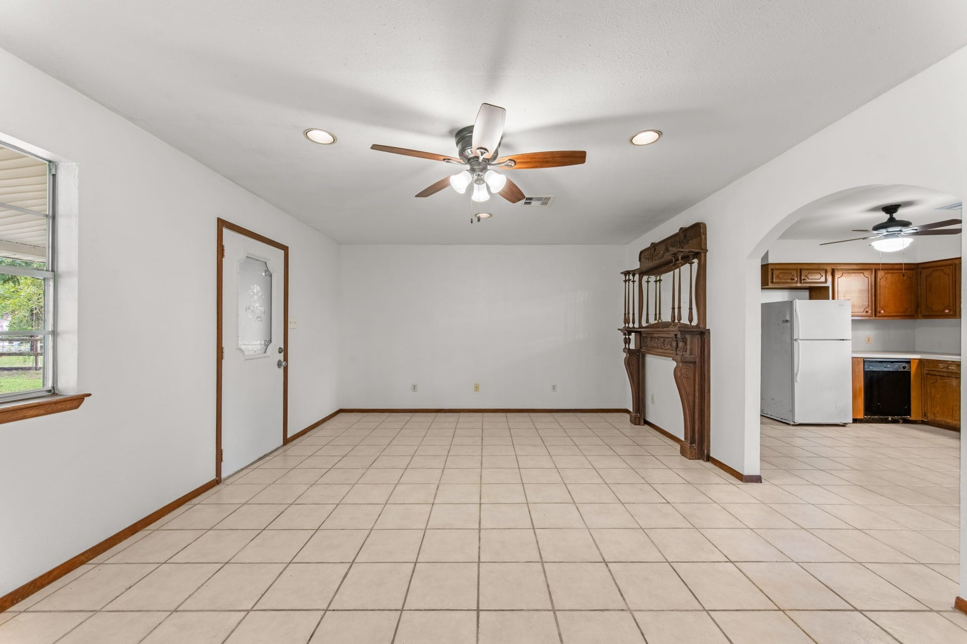 11325 32nd Street, Santa Fe, TX 77510 Another perspective showcases the living room's open floor space, decorative wood mantel, and convenient connection to the kitchen through a charming arched doorway.
