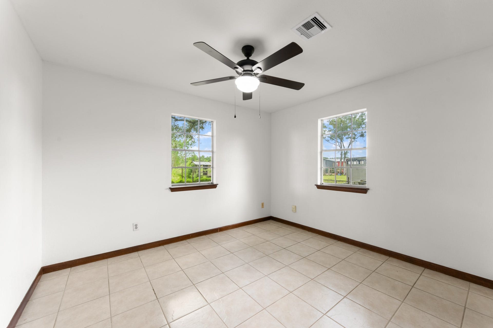 11325 32nd Street, Santa Fe, TX 77510 Bright bedroom with two windows overlooking the outdoor surroundings, neutral finishes, tile flooring, and a ceiling fan.