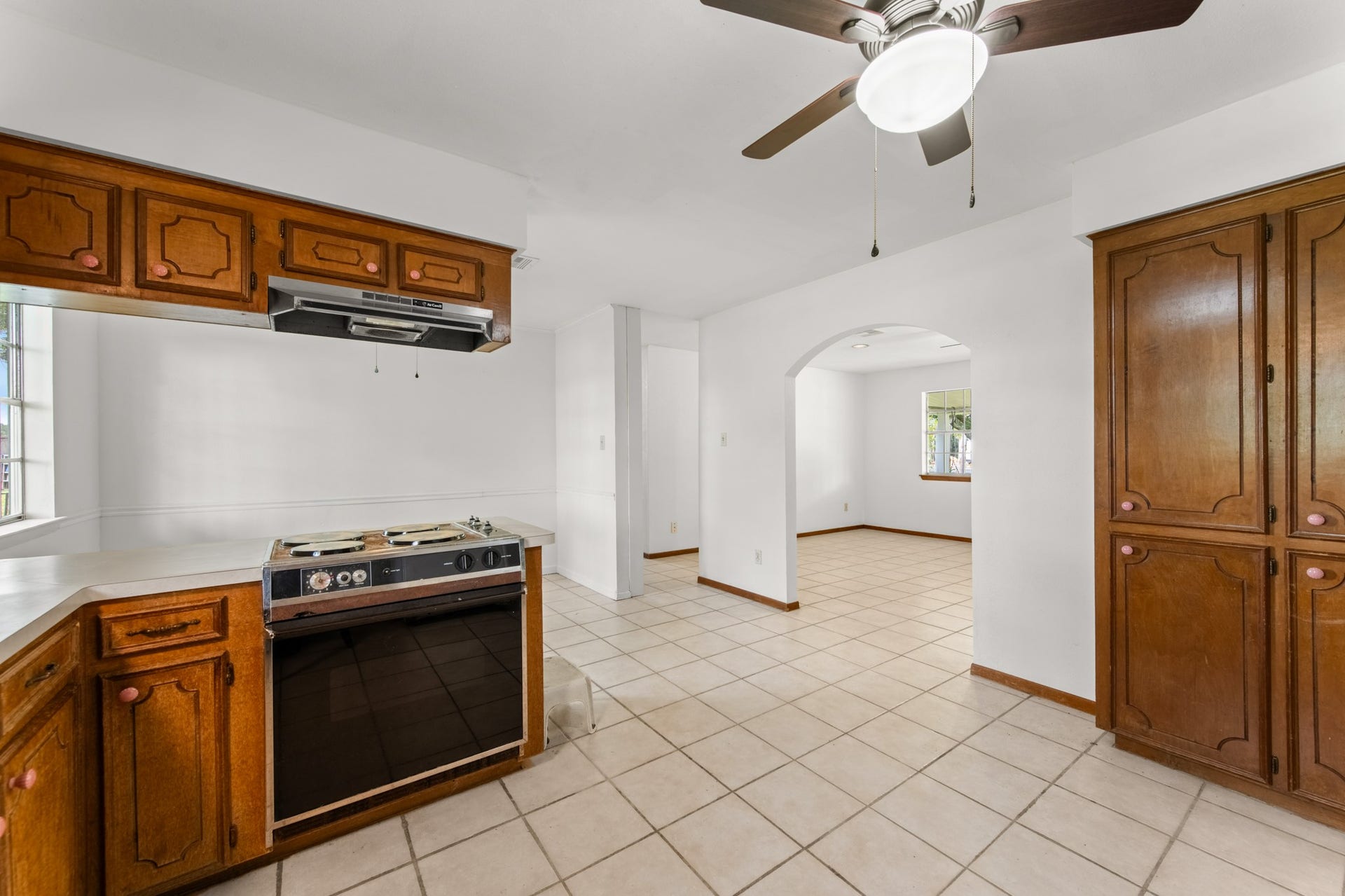 11325 32nd Street, Santa Fe, TX 77510 A view from the kitchen highlights the electric range, additional cabinet storage, and charming arched doorway connecting to the adjacent living space.