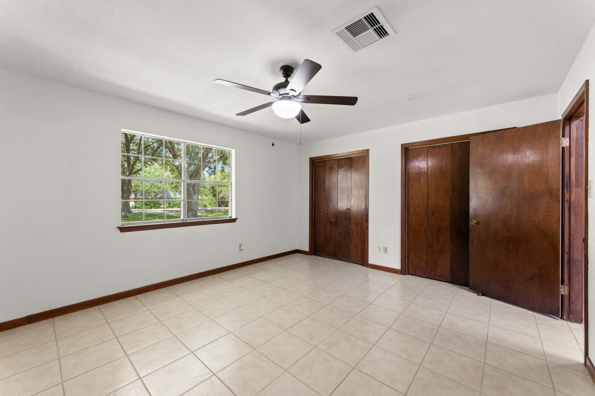 11325 32nd Street, Santa Fe, TX 77510 Natural light fills the primary bedroom, with views of mature trees, warm wood trim, and generous closet space.
