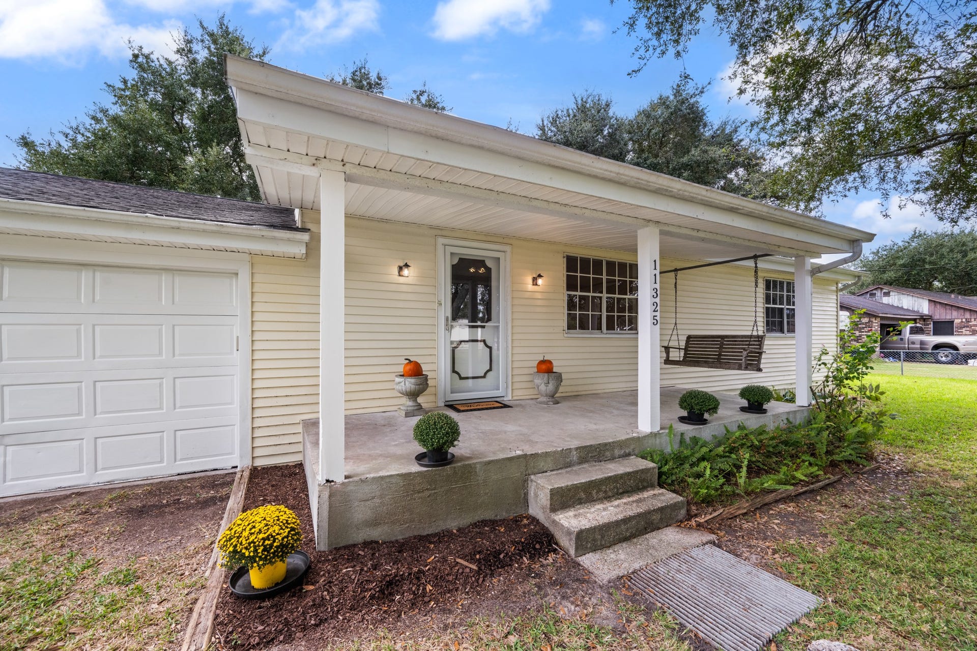 11325 32nd Street, Santa Fe, TX 77510 Welcoming covered front porch featuring a porch swing, landscaped flower beds, and an inviting entryway. A charming spot to relax and enjoy the outdoors.