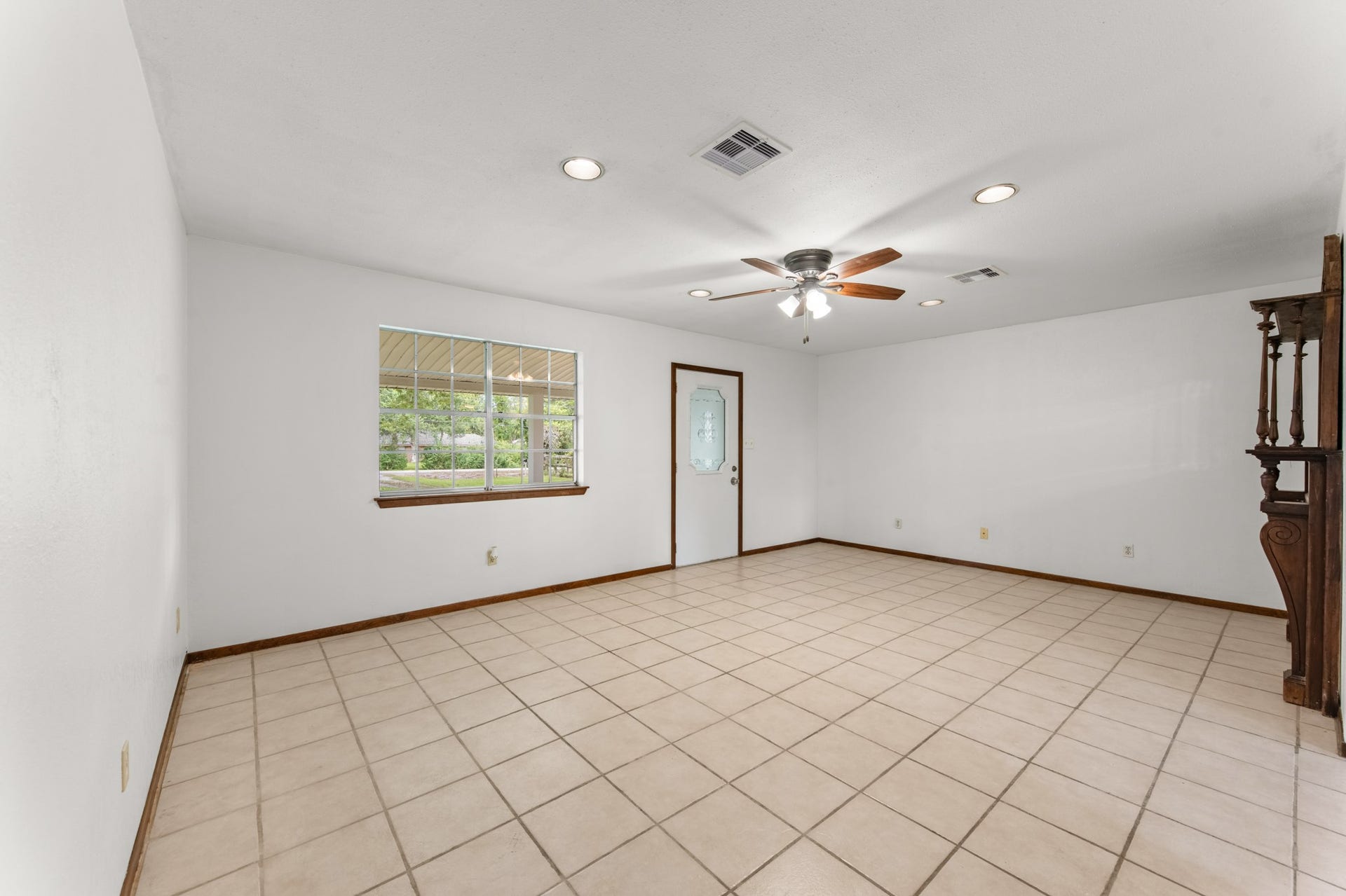 11325 32nd Street, Santa Fe, TX 77510 Generously sized living room with neutral walls, easy-care tile flooring, and a ceiling fan. The large window offers views of the covered front porch and mature trees.