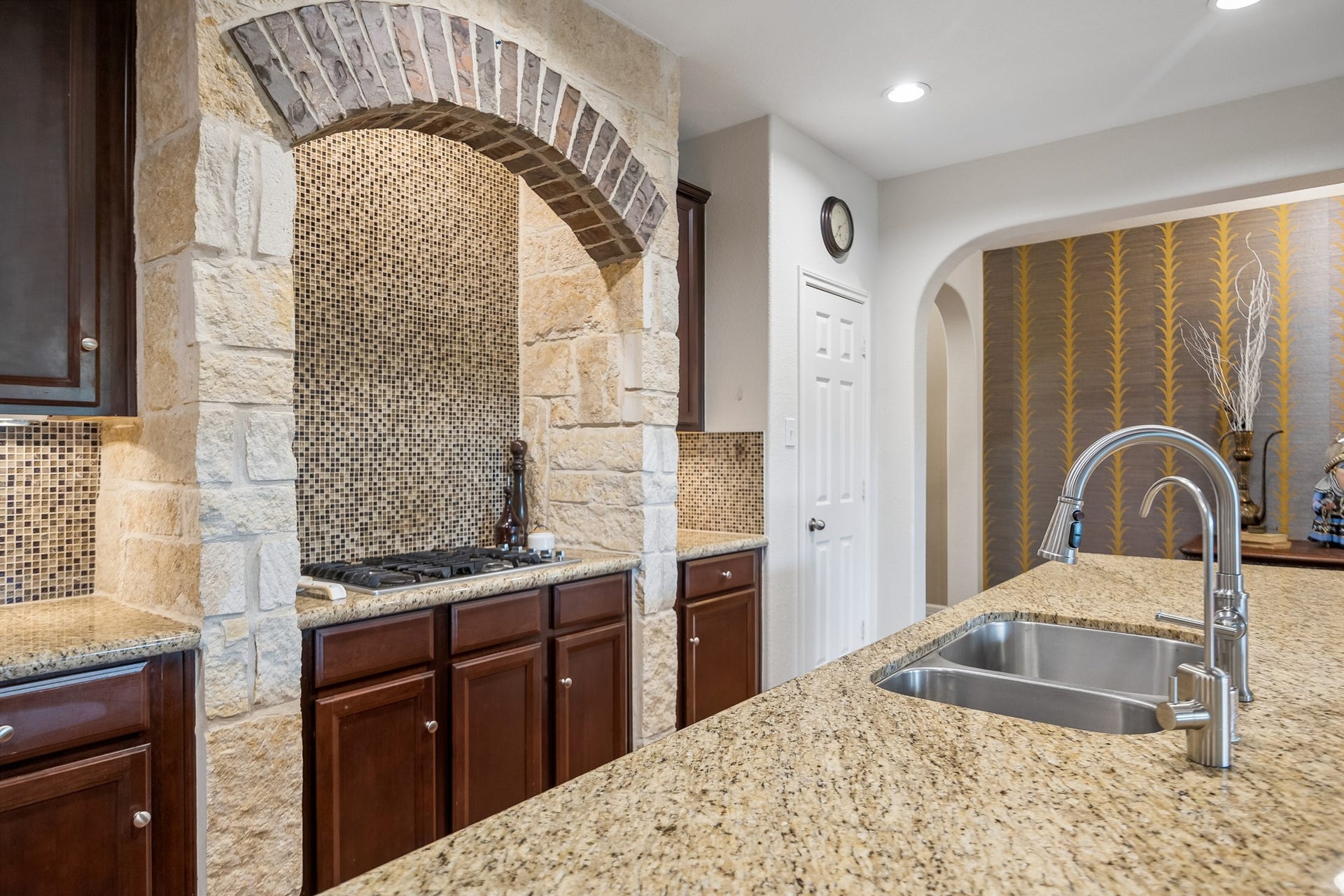 3102 London Lane, Missouri City, TX 77459 The stone and brick accents mirror the exterior finishes; glass mosaic tile create the backsplash.
