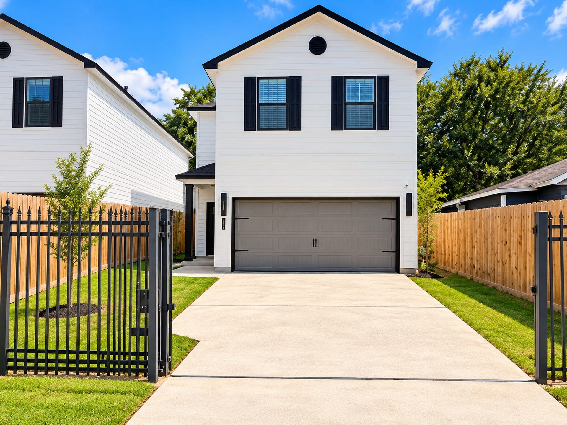 Charming two-story home with a modern exterior, featuring a spacious two-car garage and a secure gated driveway, all framed by a neatly fenced yard.