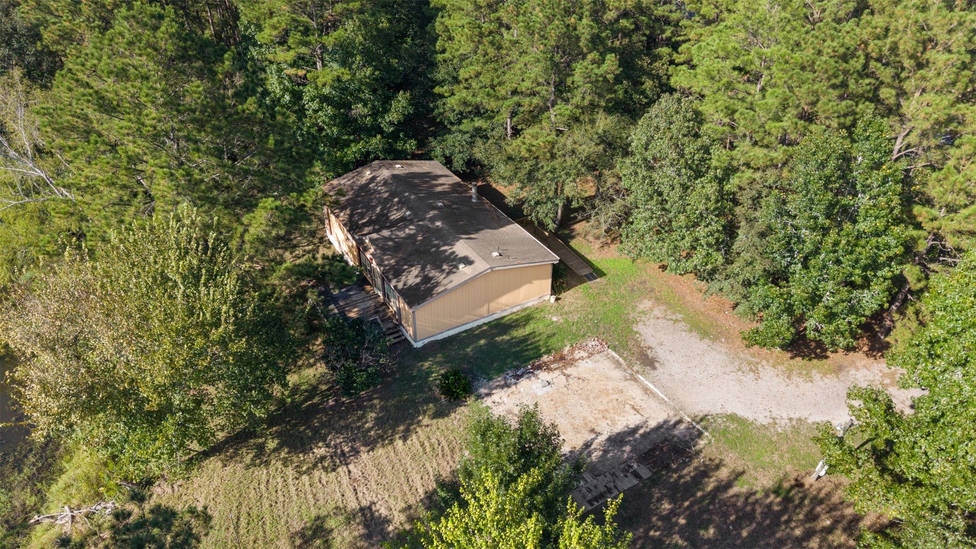 9944 Chestnut Court, Montgomery, TX 77316 A birds-eye view of the residence showcases the surrounding grounds, with a generous clearing offering flexibility for parking, outdoor projects, or future improvements.
