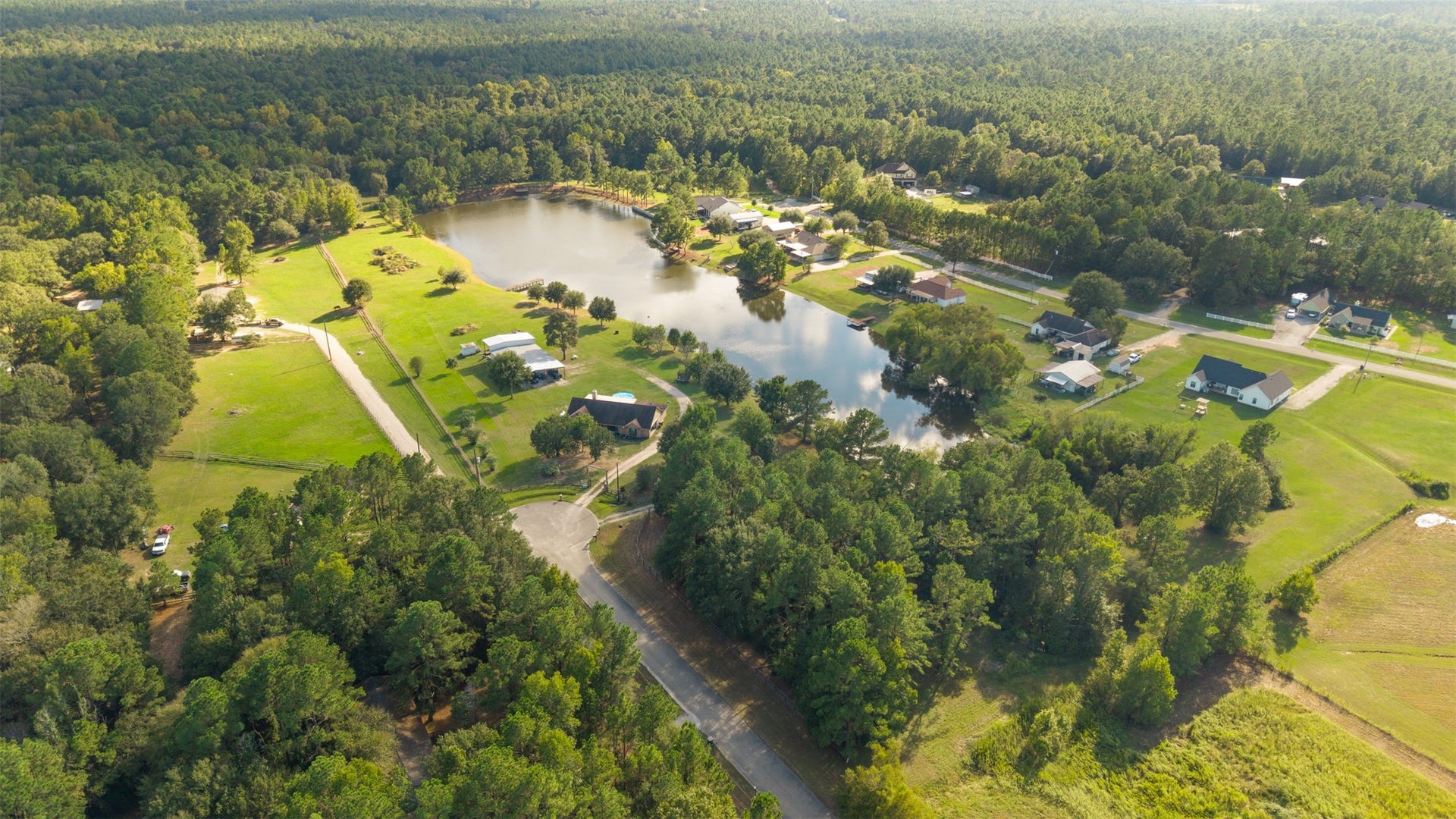 9944 Chestnut Court, Montgomery, TX 77316 A stunning aerial view showcases the beautiful, shared pond at the heart of Stone Ranch, surrounded by expansive green spaces, mature trees, and spacious homesites that create a peaceful country setting.
