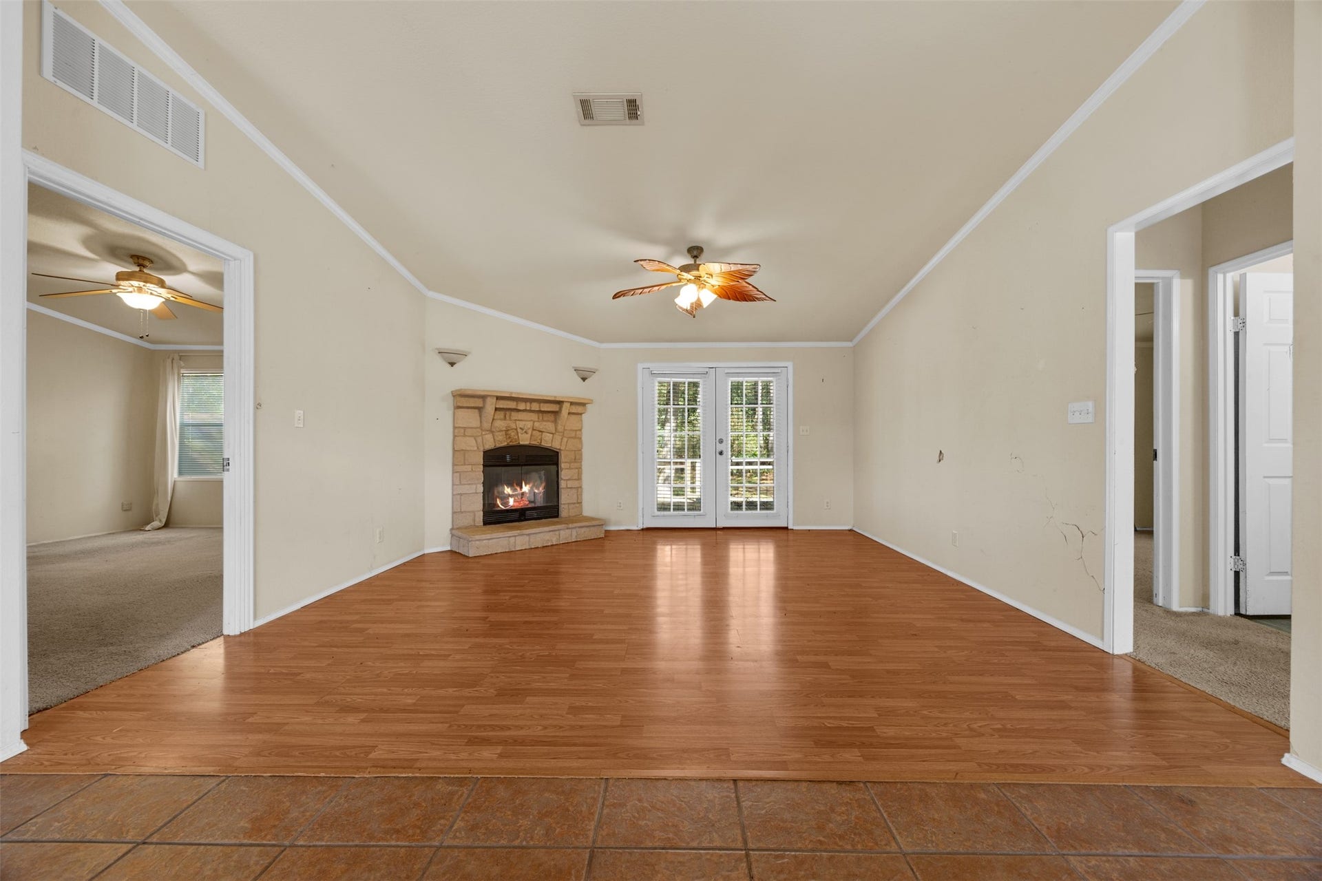 9944 Chestnut Court, Montgomery, TX 77316 The spacious living room features warm wood-look flooring, a charming stone fireplace, and French doors opening to the outdoor deck. A versatile layout offers plenty of possibilities for updating and personalizing the space.