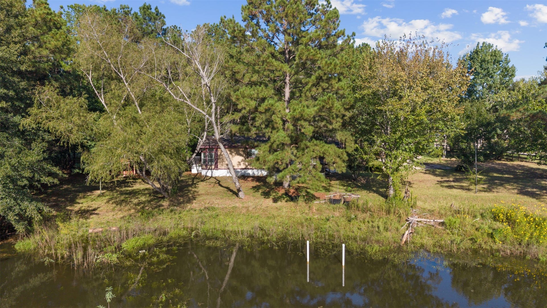 9944 Chestnut Court, Montgomery, TX 77316 A picturesque view from across the shared pond showcases the home's private, wooded setting, where mature trees and natural surroundings create a peaceful retreat.