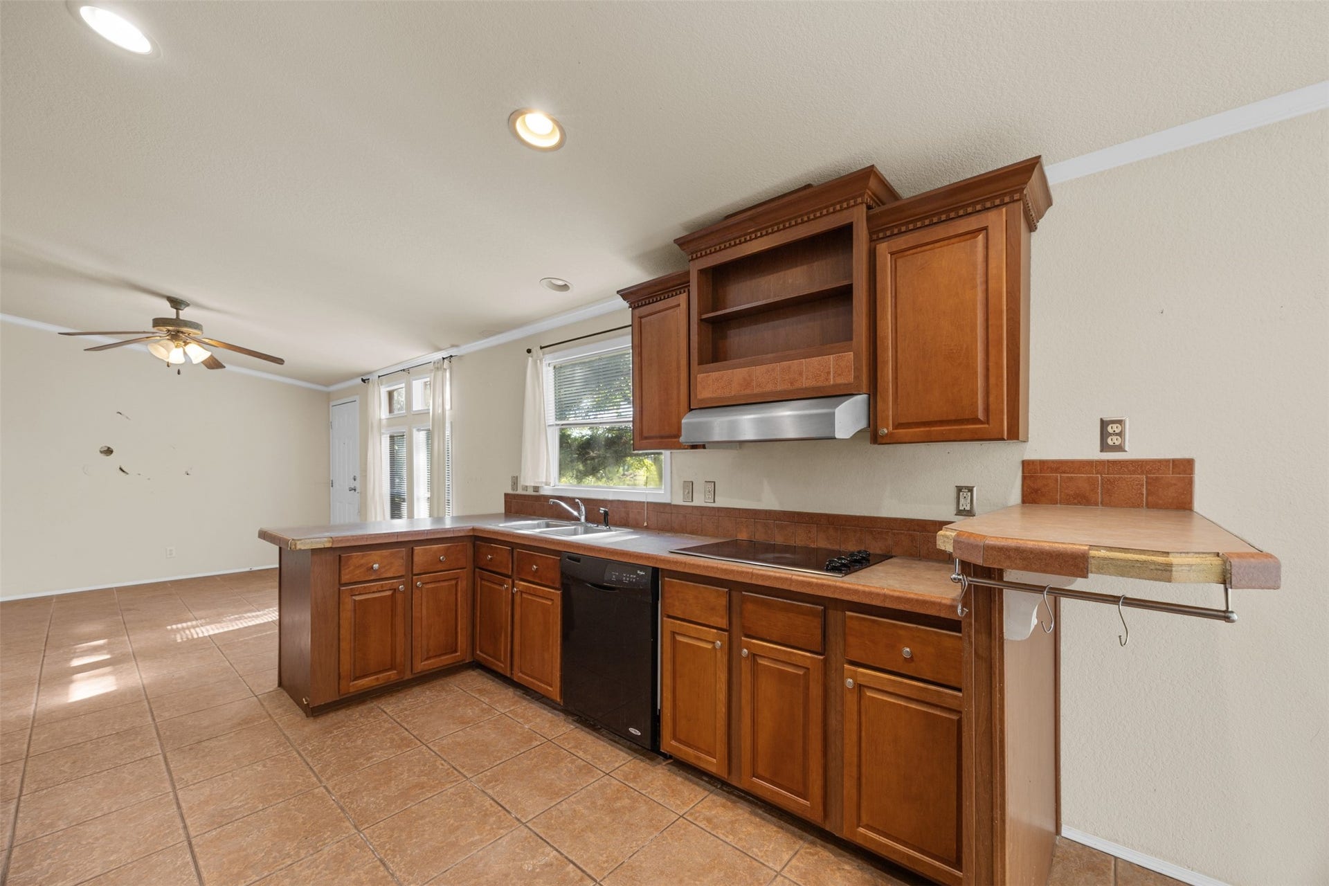 9944 Chestnut Court, Montgomery, TX 77316 Another view of the kitchen highlights the warm wood cabinetry, built-in cooktop, and convenient counter space overlooking the adjoining dining area. A functional layout with plenty of potential for personalization.