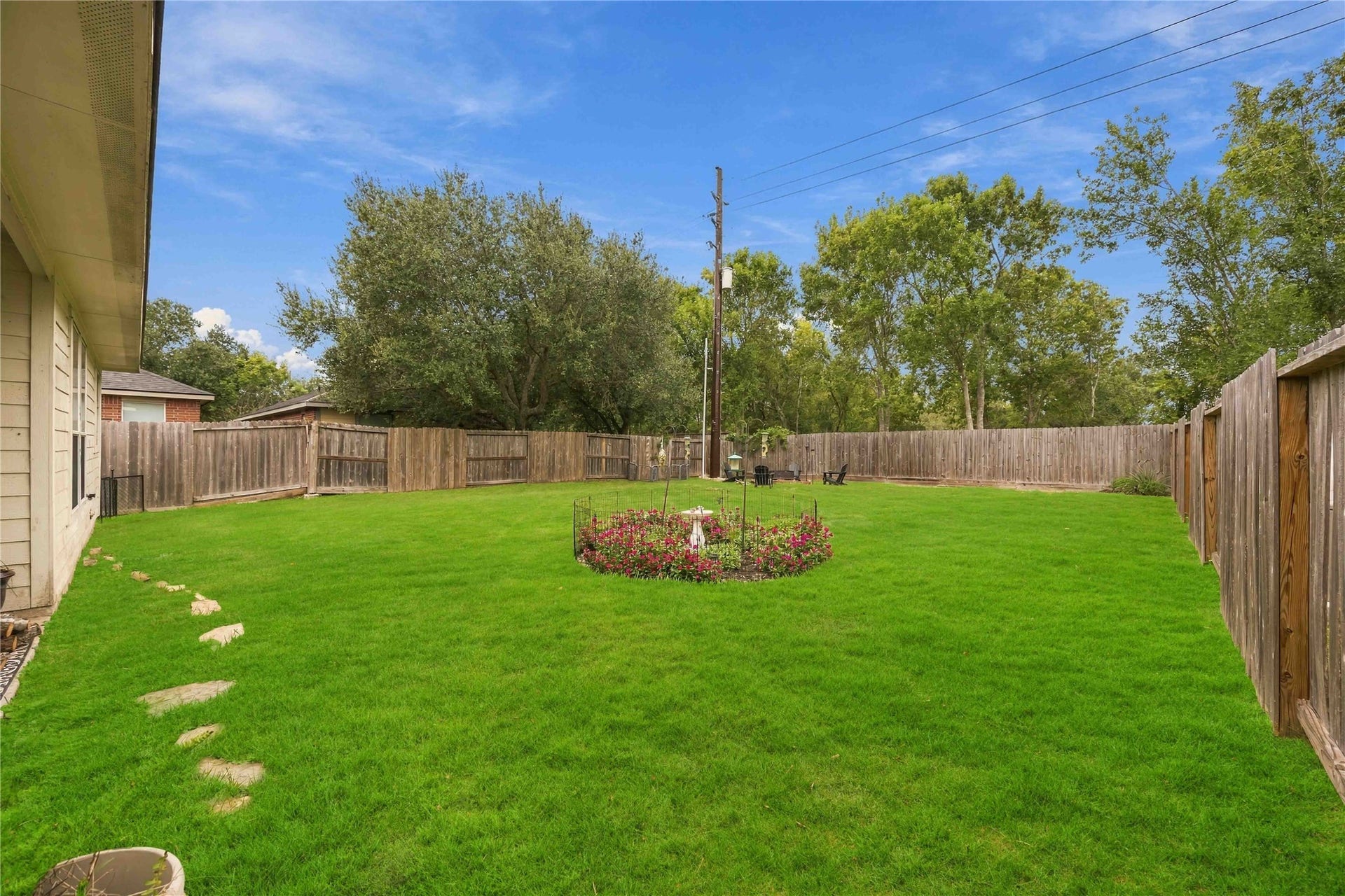 11415 English Rose Trail, Missouri City, TX 77459 Generously sized backyard with a lush green lawn, perimeter wood fencing, and landscaped garden bed.