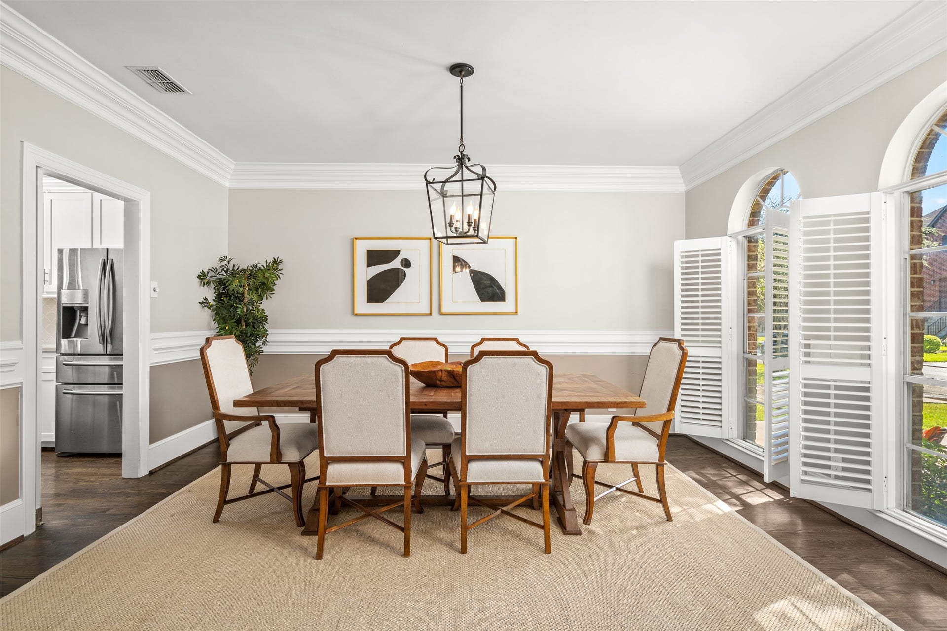4312 Holt Street, Bellaire, TX 77401 Formal dining is elevated in this light-filled room, framed by dramatic crown molding and classic chair rail detailing. Arched windows with plantation shutters showcase leafy views and flood the space with natural light.