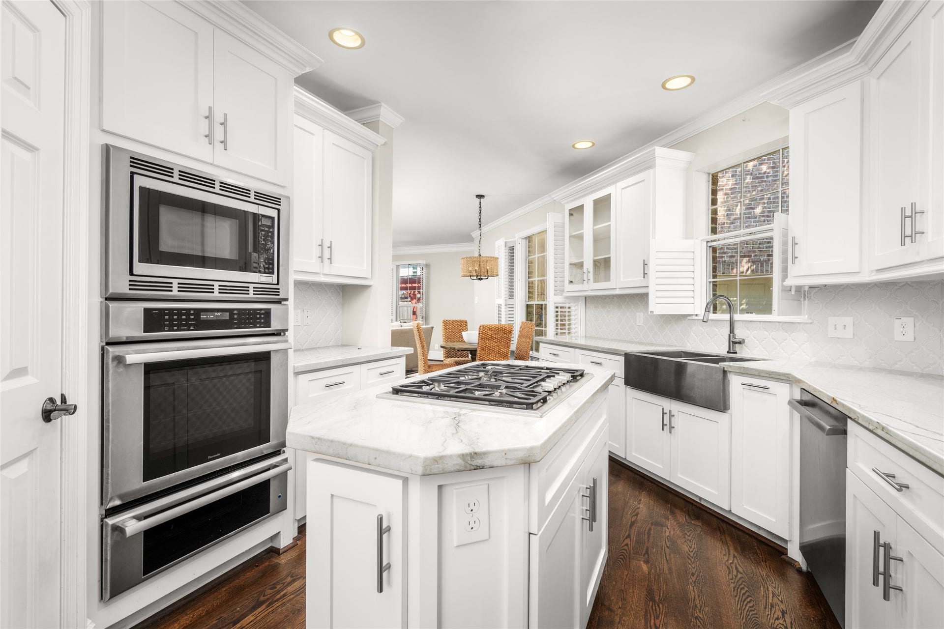 4312 Holt Street, Bellaire, TX 77401 Designed for both everyday living and entertaining, the kitchen features crisp white shaker cabinetry, stone countertops, and a charming arabesque tile backsplash. A stainless farmhouse apron-front sink, stainless appliances, and a gas cooktop on the center island complete the look.