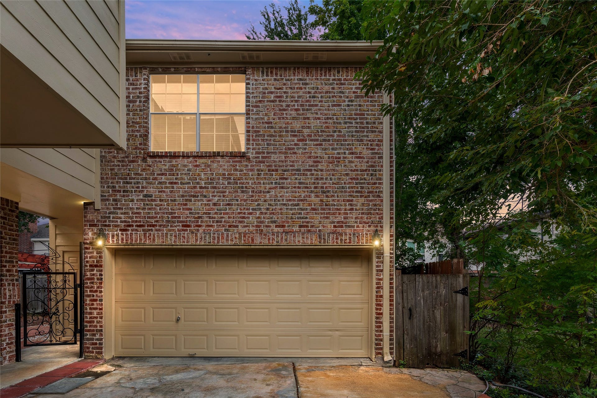 4312 Holt Street, Bellaire, TX 77401 A two-car garage with carriage-style lanterns, and a decorative wrought-iron gate that opens to the private backyard.
