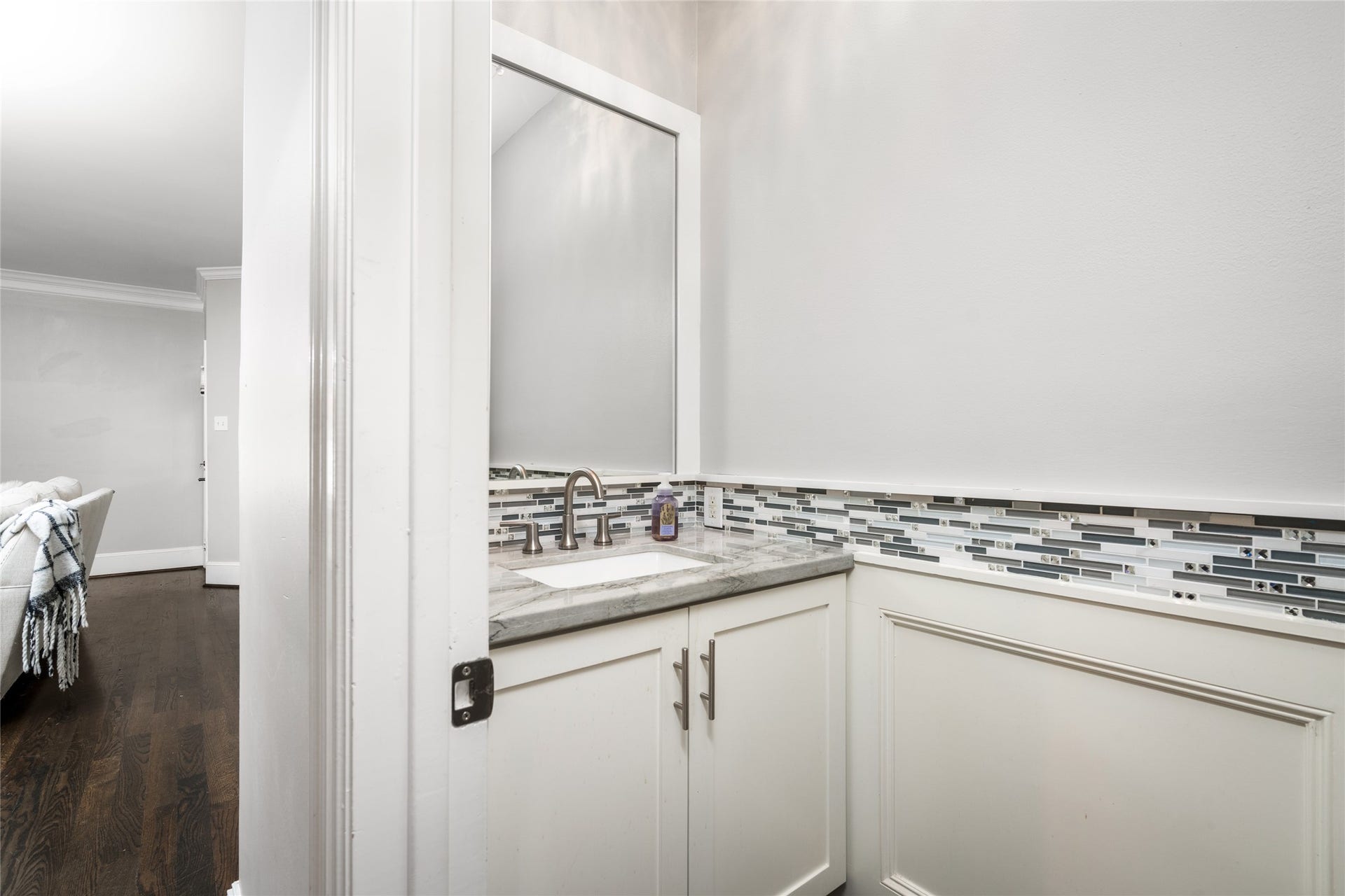 4312 Holt Street, Bellaire, TX 77401 This stylish powder bath sparkles with a glass mosaic tile border, an undermount sink, and brushed-nickel fixtures. White shaker cabinetry and wainscot-style paneling keep the look crisp and timeless.