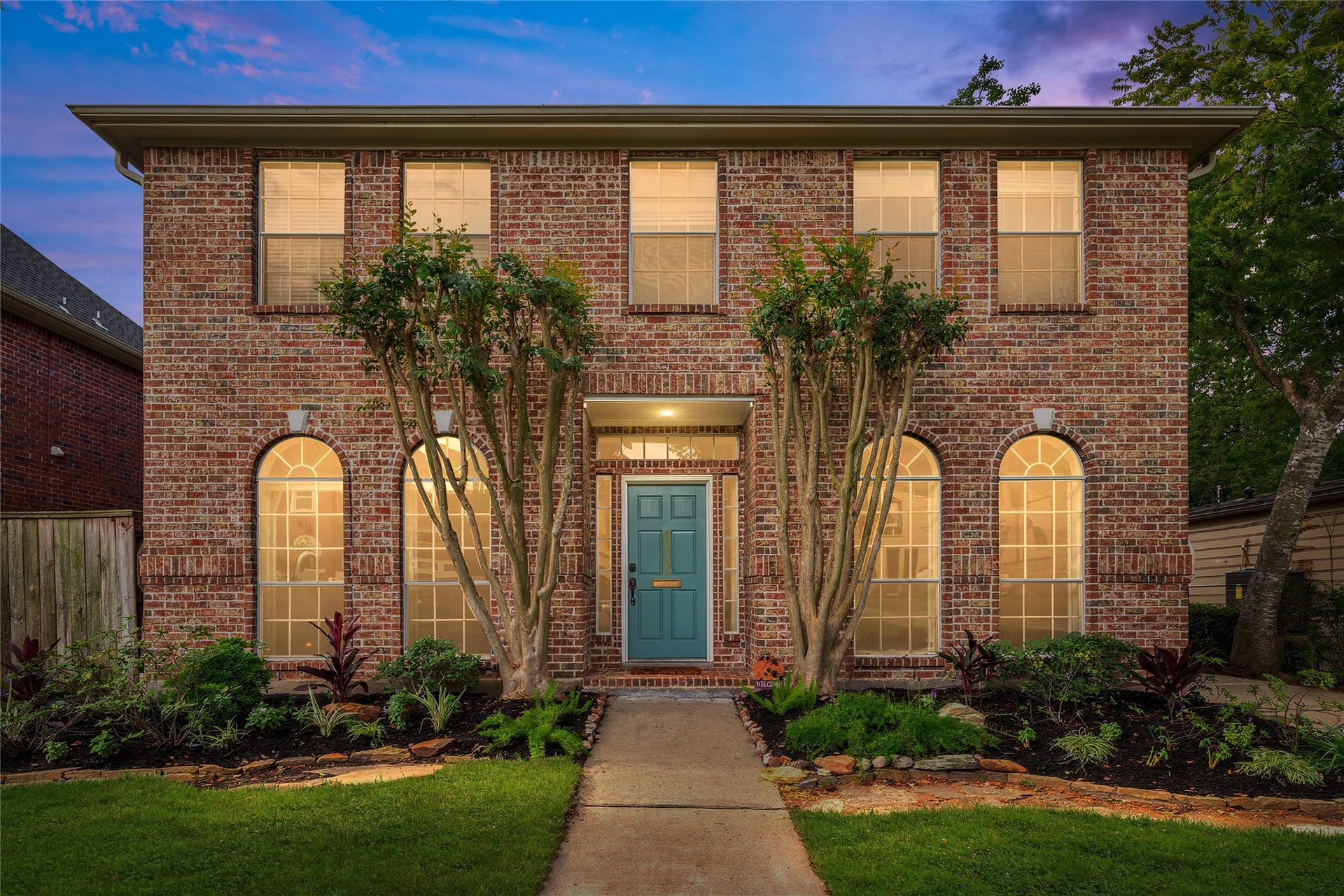 4312 Holt Street, Bellaire, TX 77401 Arched front windows and tall second-story windows, plus a teal front door adds a pop of color against classic brick. Crepe myrtles and manicured beds complete the picture of timeless curb appeal.
