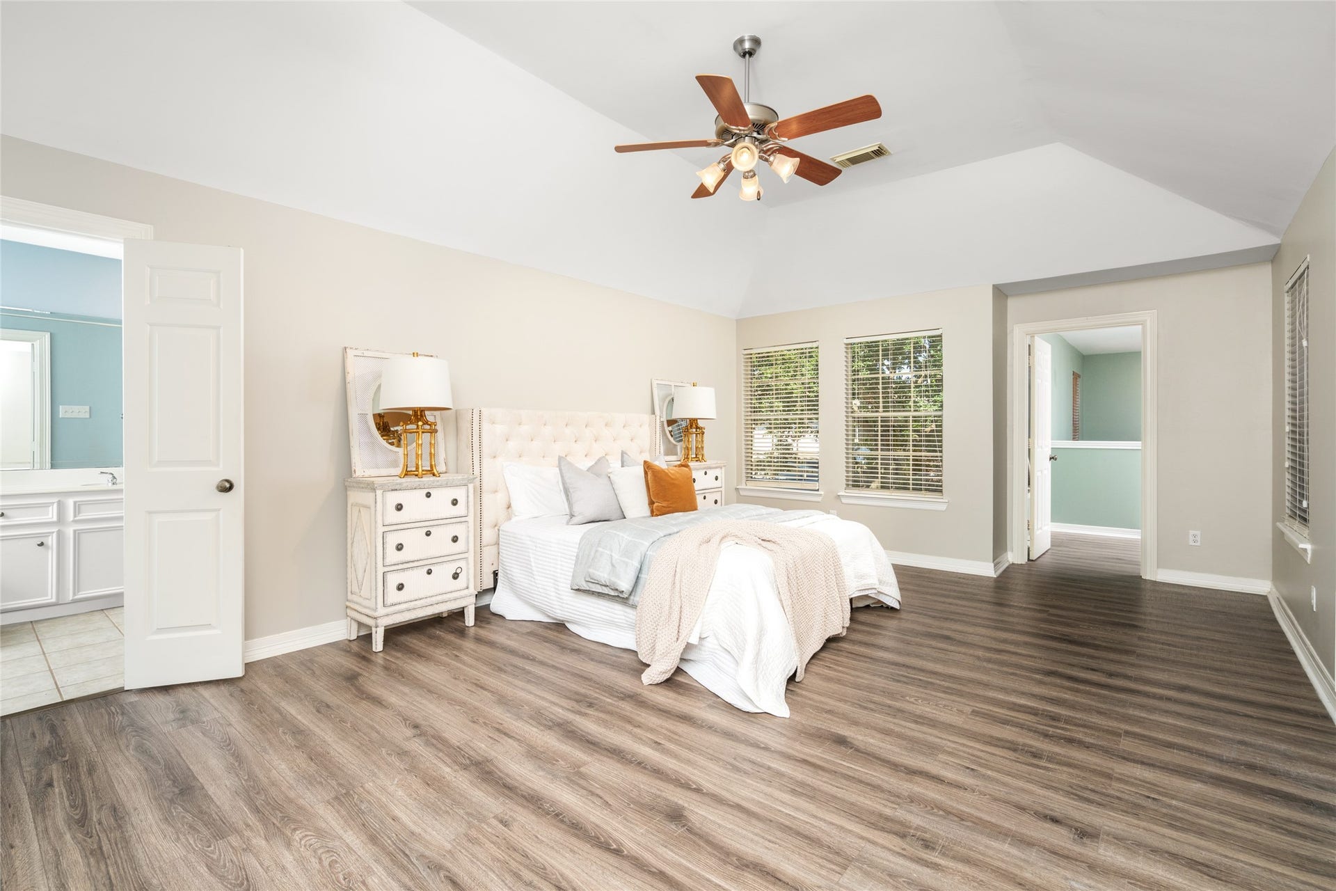4312 Holt Street, Bellaire, TX 77401 Generously proportioned and bathed in natural light, this bedroom features a tray ceiling with ceiling fan, a large window overlooking mature greenery, and a calming neutral palette. NOTE: Door on far wall leads to "nanny suite"