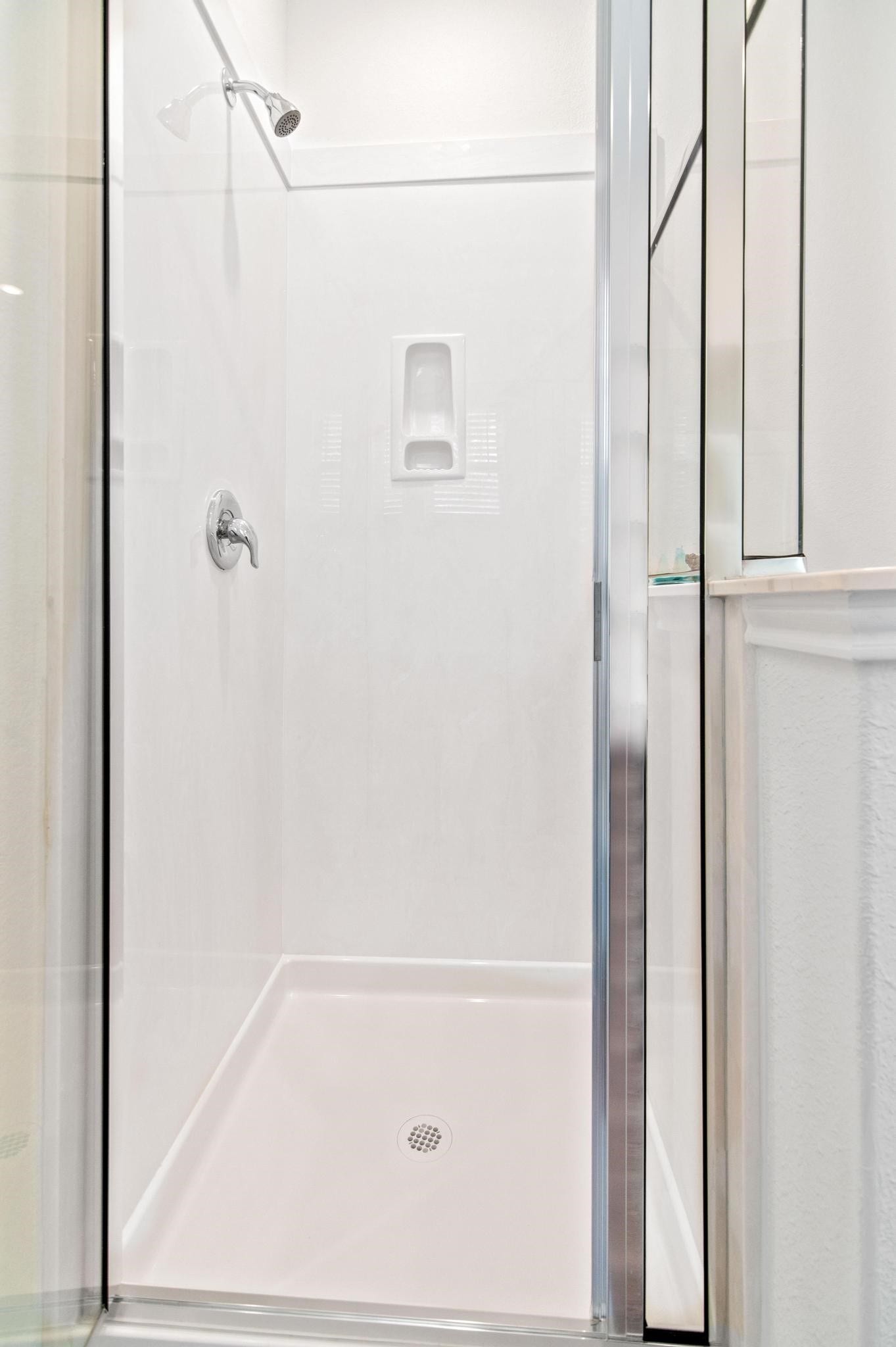 Modern shower with sleek glass doors and a convenient built-in shelf for storage.