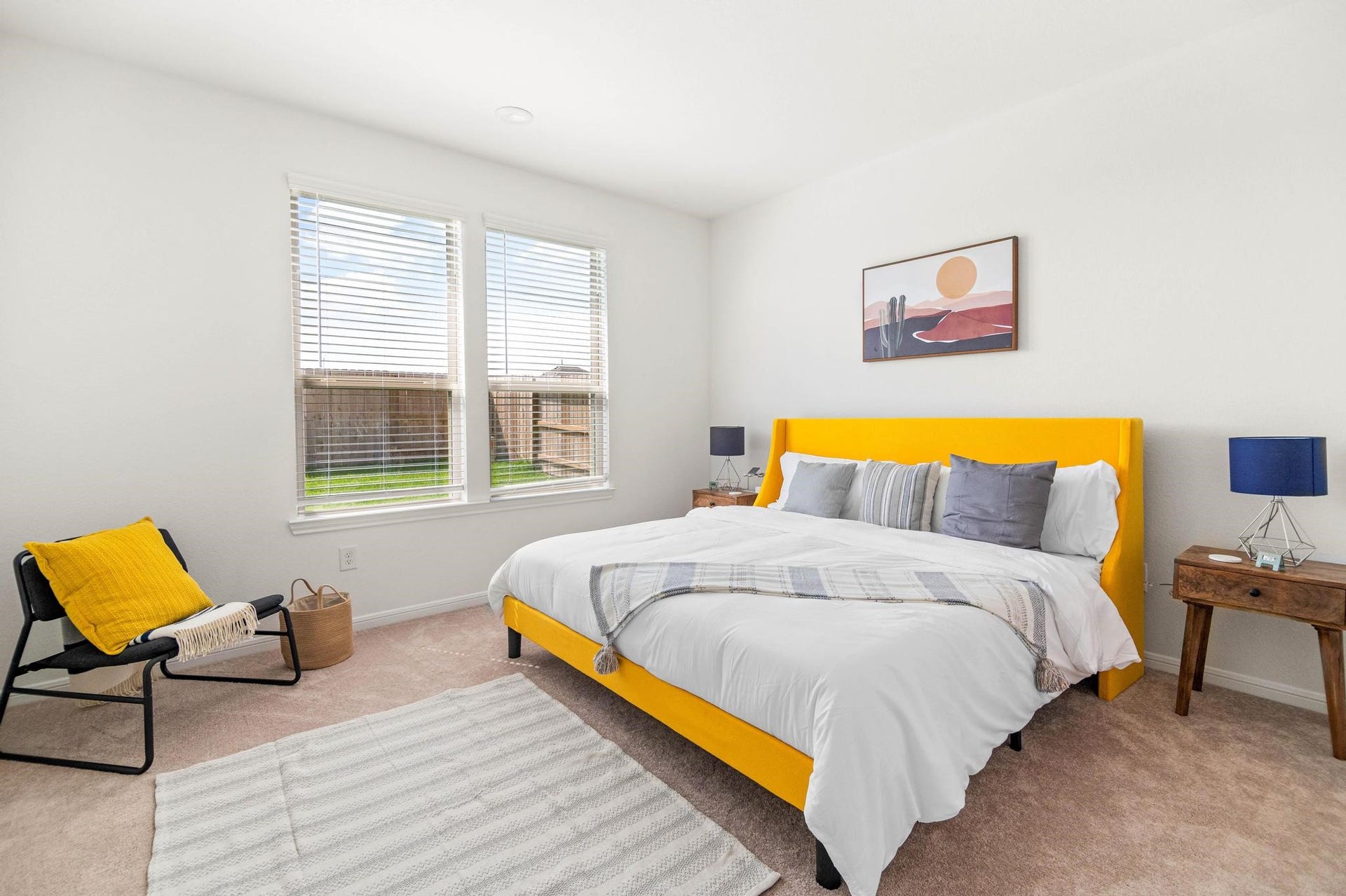 Bright and inviting bedroom featuring a bold yellow bed frame, cozy bedding, and ample natural light from large windows.