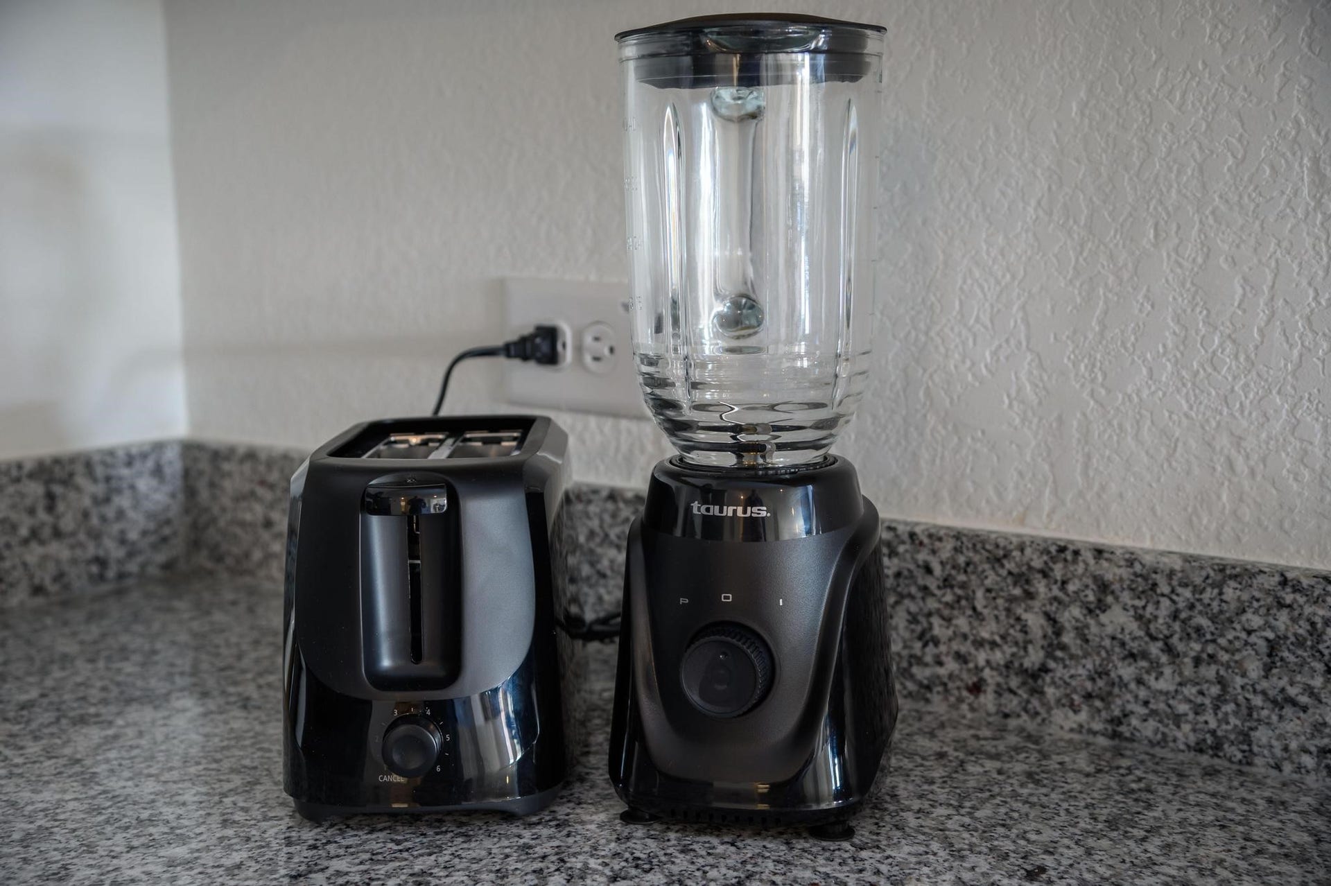 Modern kitchen corner with sleek granite countertops, featuring a black toaster and blender for convenient meal preparation.