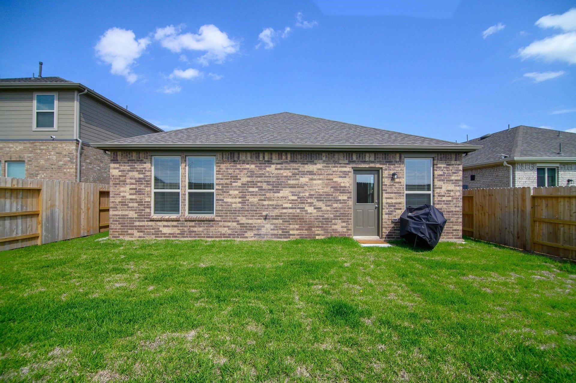 Charming brick exterior with a neatly maintained backyard, perfect for outdoor gatherings.