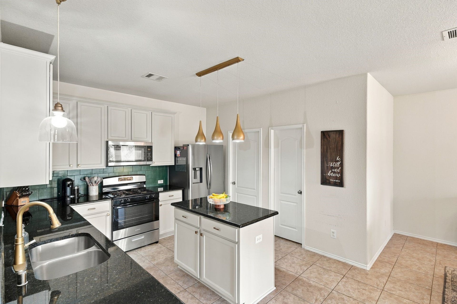 26037 Kings Mill Crest Drive, Kingwood, TX 77339 Modern kitchen with sleek black countertops, stainless steel appliances, and stylish pendant lighting.