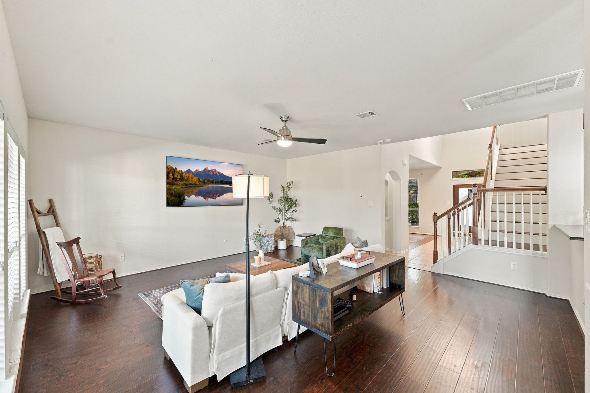26037 Kings Mill Crest Drive, Kingwood, TX 77339 Spacious living room with elegant hardwood floors, abundant natural light, and a stylish ceiling fan, complemented by a modern staircase and cozy seating area.