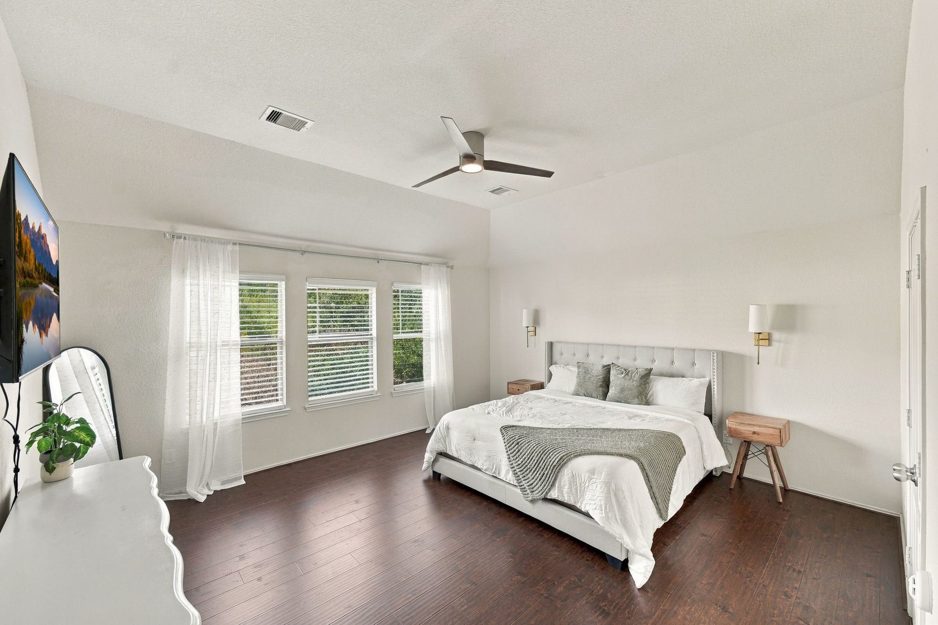 26037 Kings Mill Crest Drive, Kingwood, TX 77339 Spacious and bright primary bedroom featuring rich hardwood floors, a large bed with plush bedding, and ample natural light streaming through multiple windows.