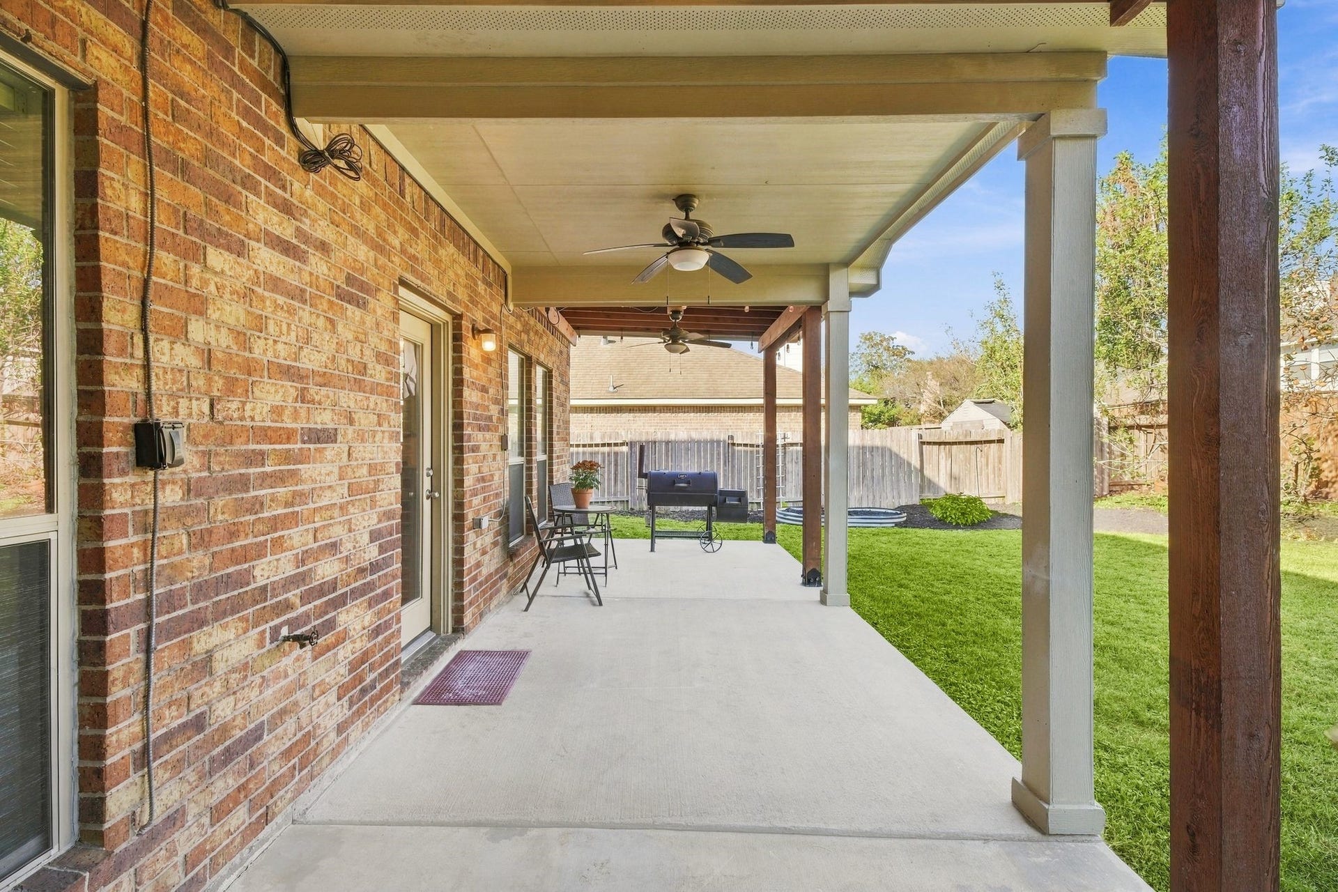 26037 Kings Mill Crest Drive, Kingwood, TX 77339 Spacious covered patio with ceiling fans, perfect for outdoor relaxation, overlooks a lush, well-maintained backyard.
