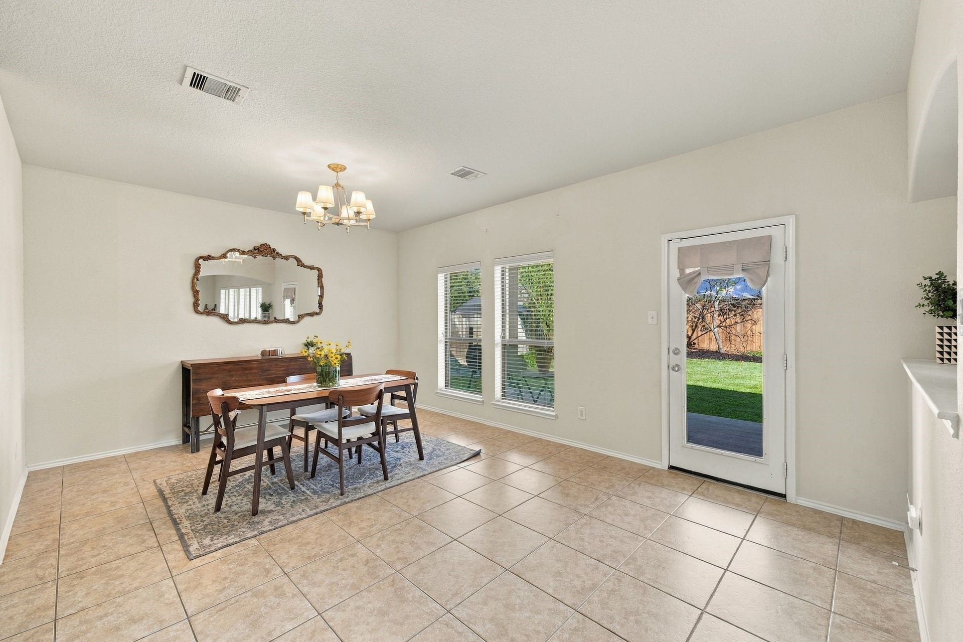 26037 Kings Mill Crest Drive, Kingwood, TX 77339 Bright and inviting dining area with tile flooring, a charming chandelier, and double windows allowing natural light to flood the space. The room features a stylish dining set and direct access to a lush backyard through a glass door.