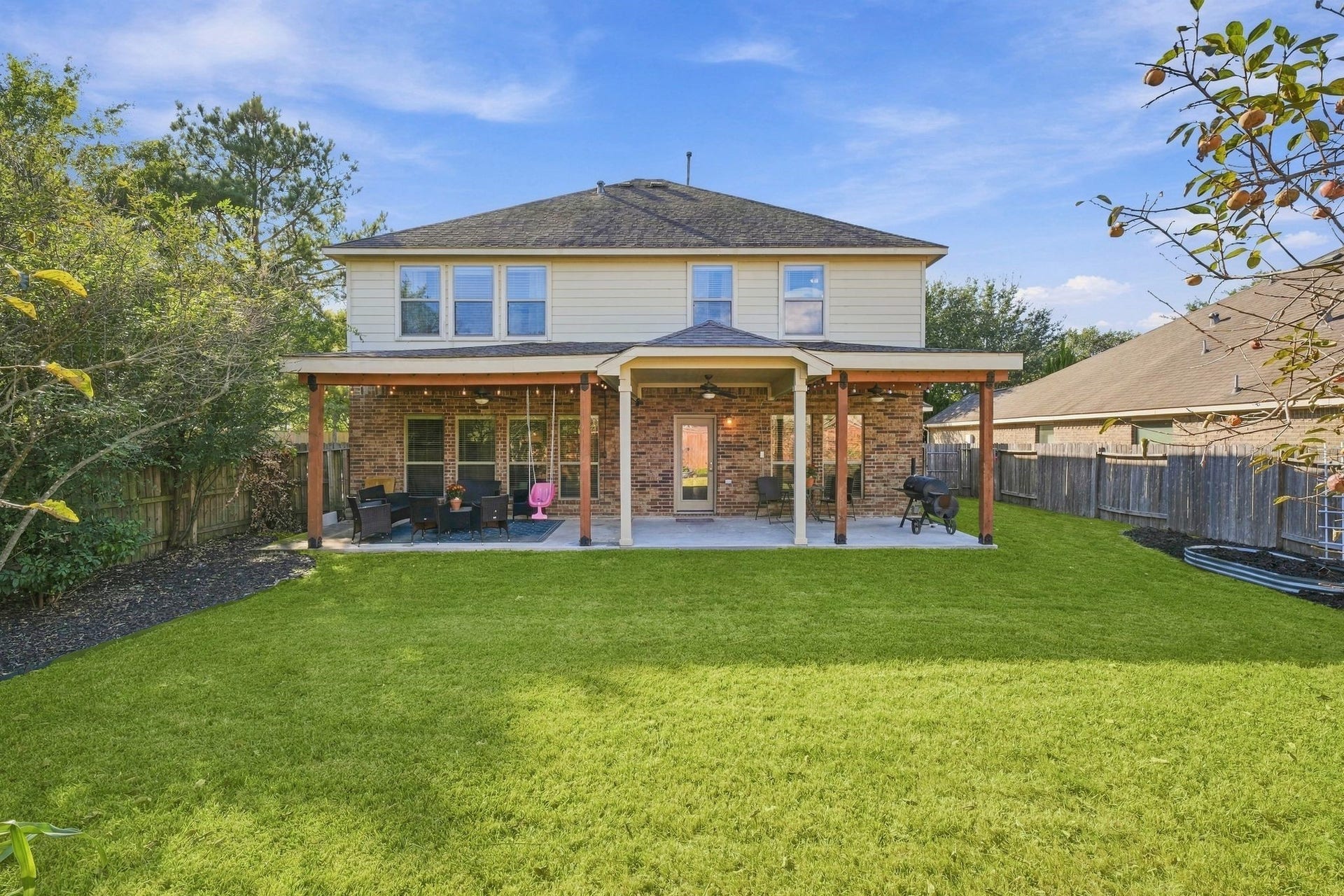 26037 Kings Mill Crest Drive, Kingwood, TX 77339 Charming two-story home with a spacious covered patio overlooking a lush, well-manicured backyard, perfect for outdoor entertaining and relaxation.