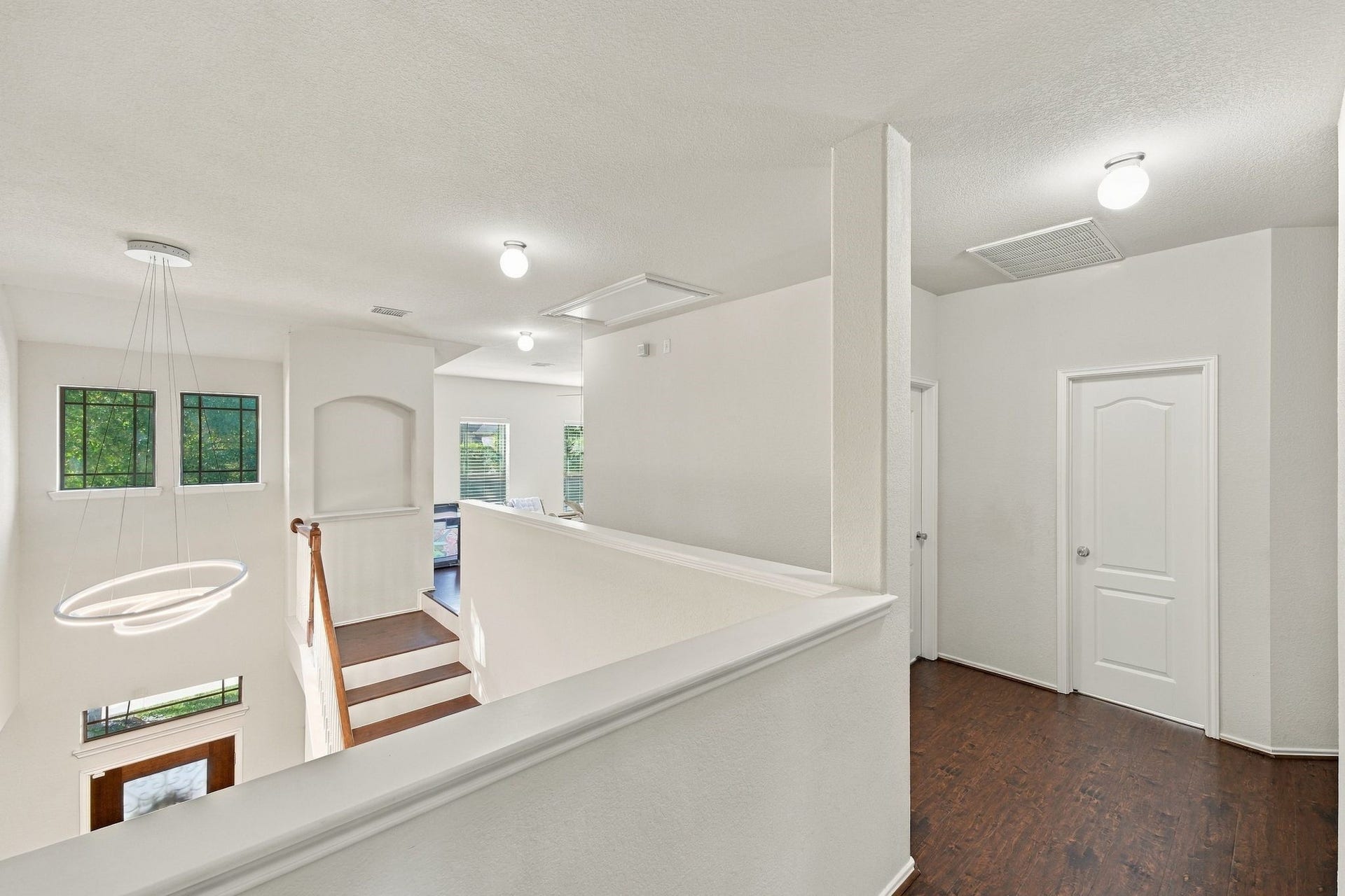 26037 Kings Mill Crest Drive, Kingwood, TX 77339 Bright and airy upstairs landing with modern lighting, elegant wood flooring, and multiple doorways leading to additional rooms.