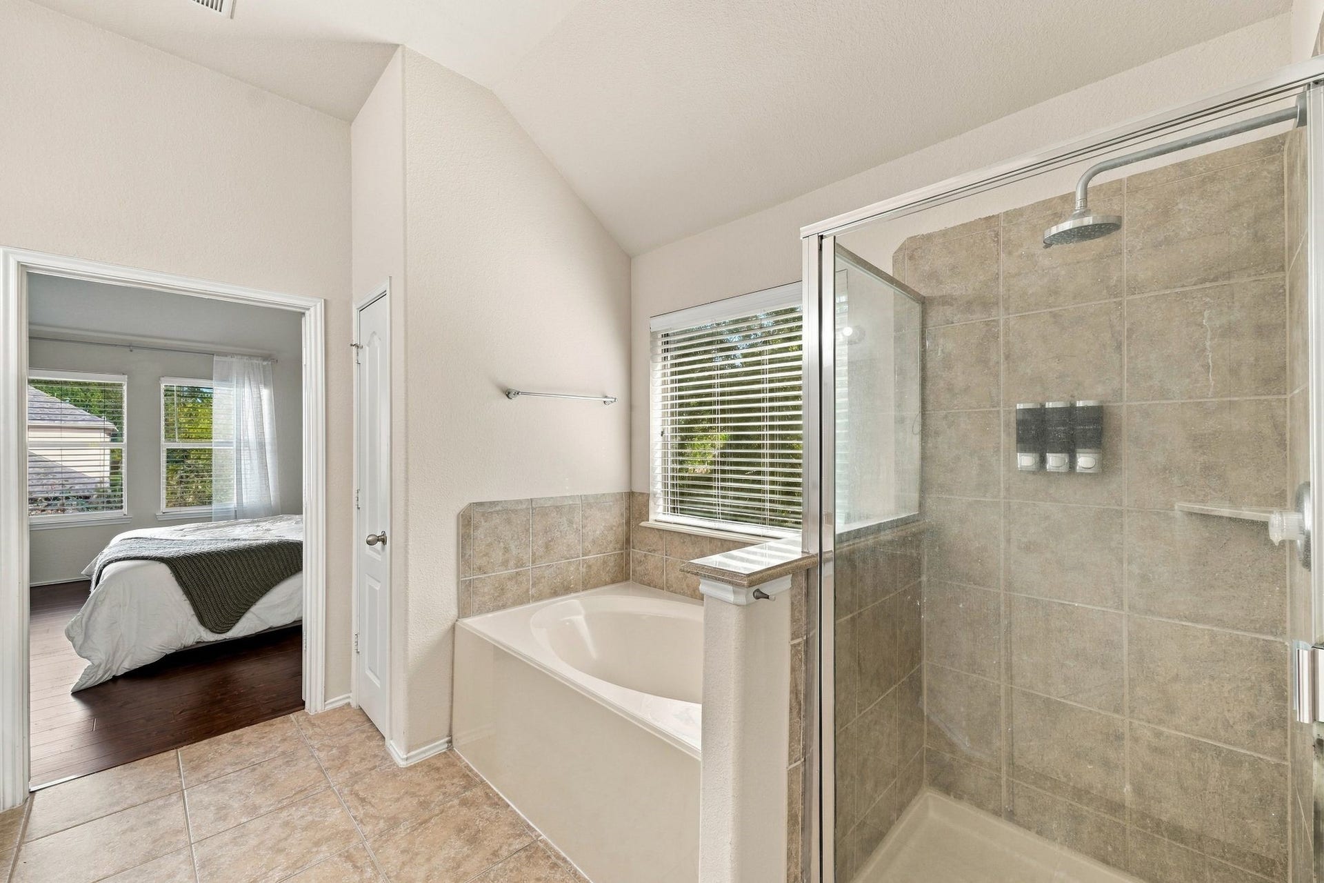 26037 Kings Mill Crest Drive, Kingwood, TX 77339 Bright primary bathroom featuring a spacious glass-enclosed shower, separate soaking tub, and tile flooring, with direct access to the primary bedroom.